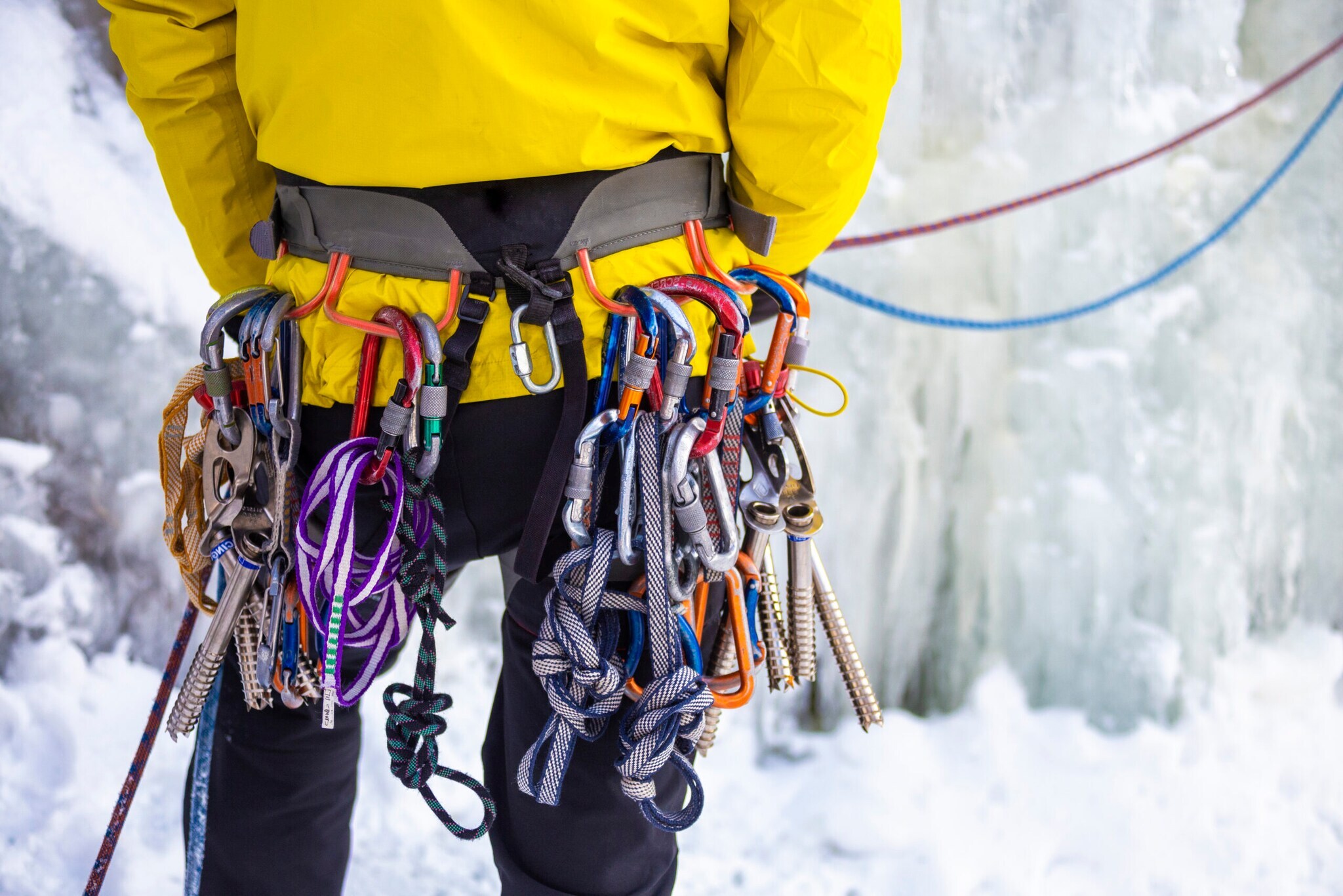 Verschiedene Haken und Seile hängen an einer Halterung um die Hüfte einer Person. Verschiedene Haken und Seile hängen an einer Halterung um die Hüfte einer Person.