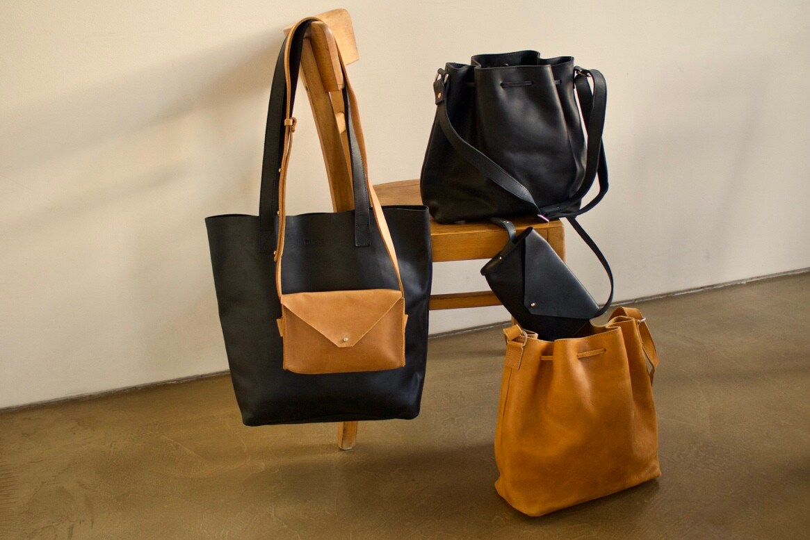 Mehrere blaue und ockerfarbene Ledertaschen auf und an einem Holzstuhl. Mehrere blaue und ockerfarbene Ledertaschen auf und an einem Holzstuhl.