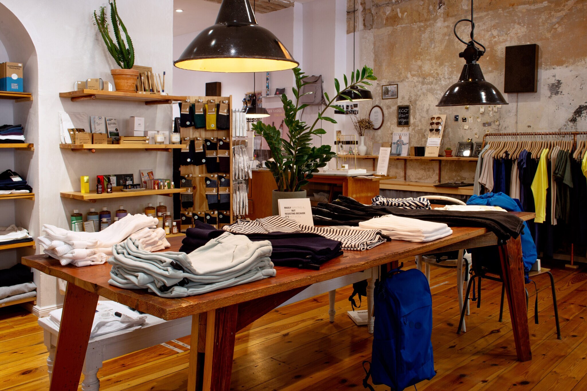 Innenansicht eines Modeladens mit Kleidung und Kosmetikartikeln.