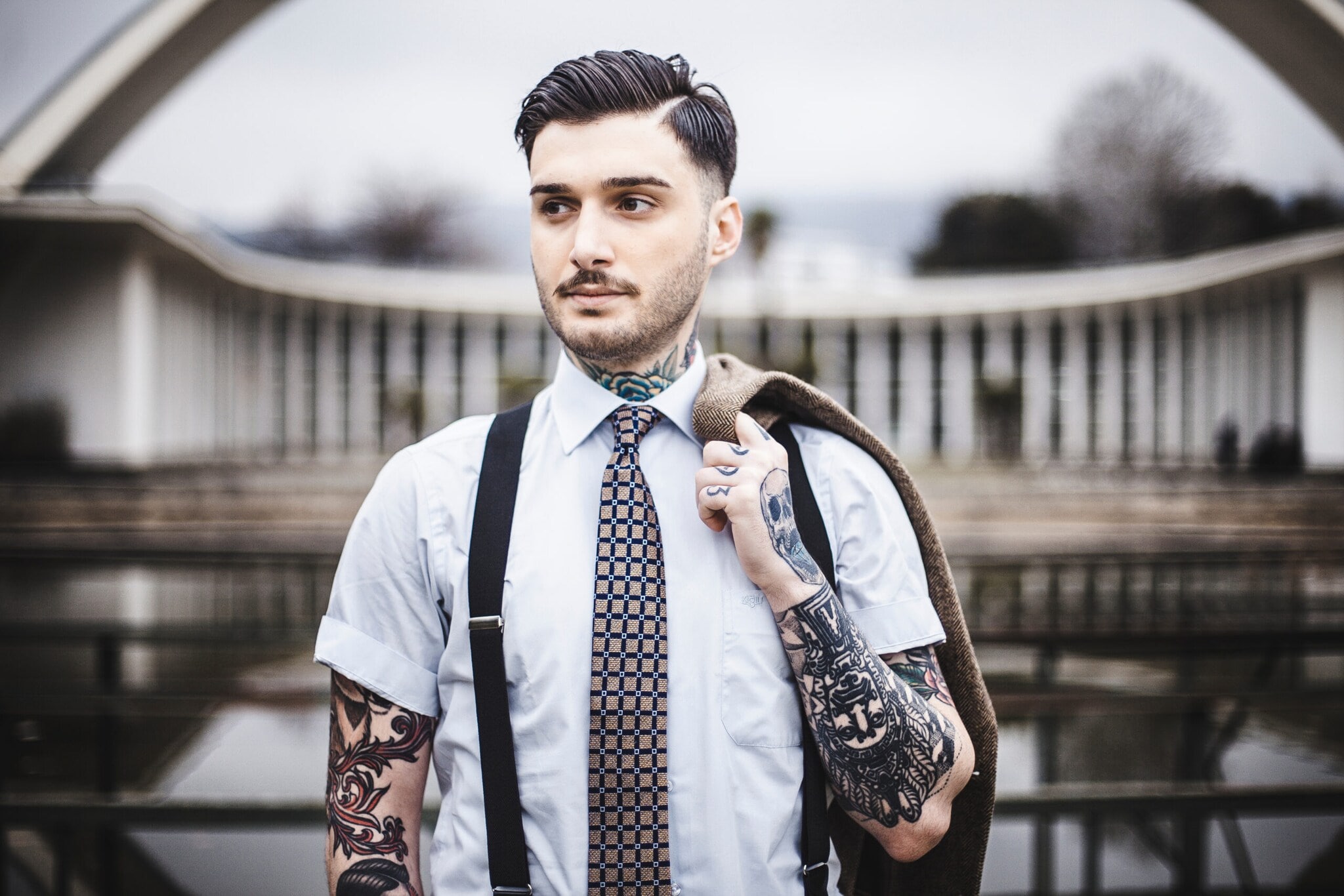 Ein junger Mann mit Tattoos trägt Hosenträger und Krawatte. Ein junger Mann mit Tattoos trägt Hosenträger und Krawatte.