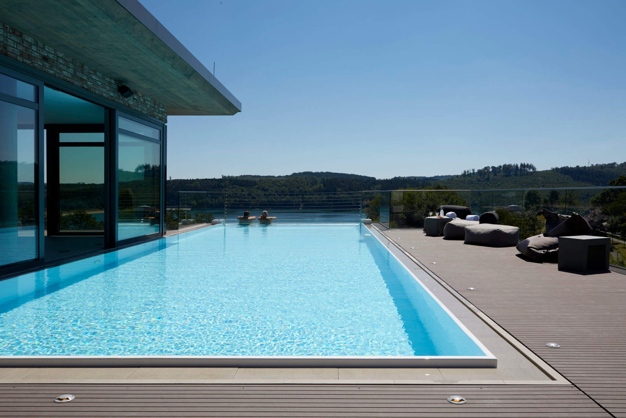 Infinitypool auf dem Dach eines Hotels, im Wasser zwei Personen, die in die Natur schauen