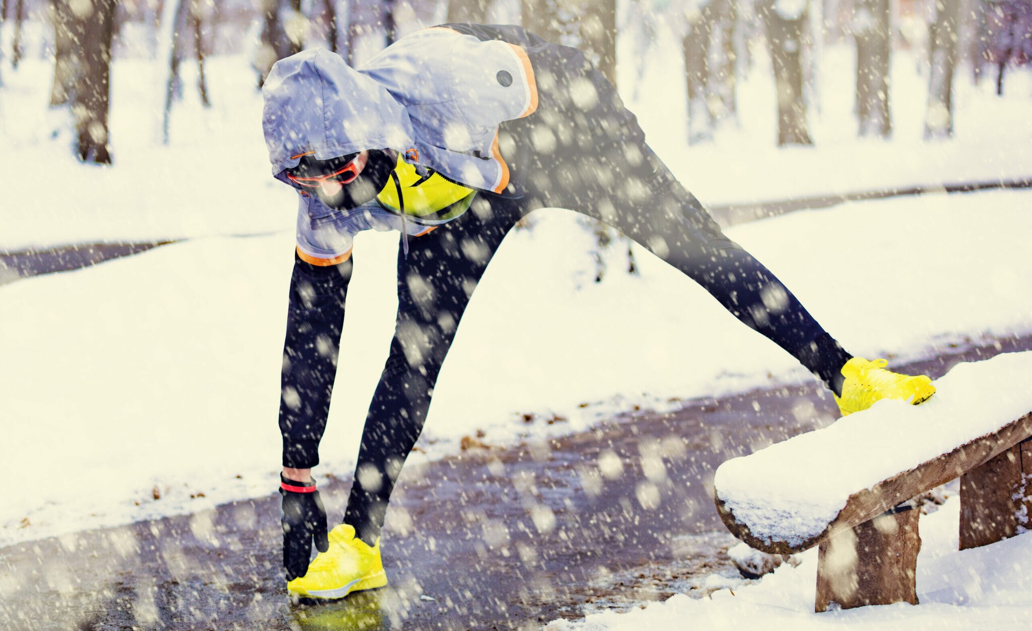 Ein sportlich gekleideter Mensch macht Stretchingübungen im Schnee.