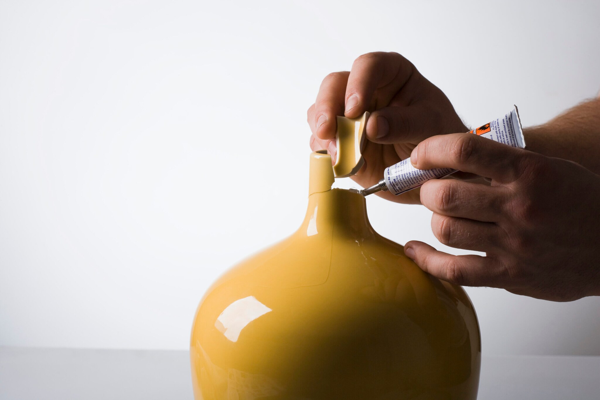 Auf die Bruchstellen einer kaputten Vase wird Kleber aufgebracht