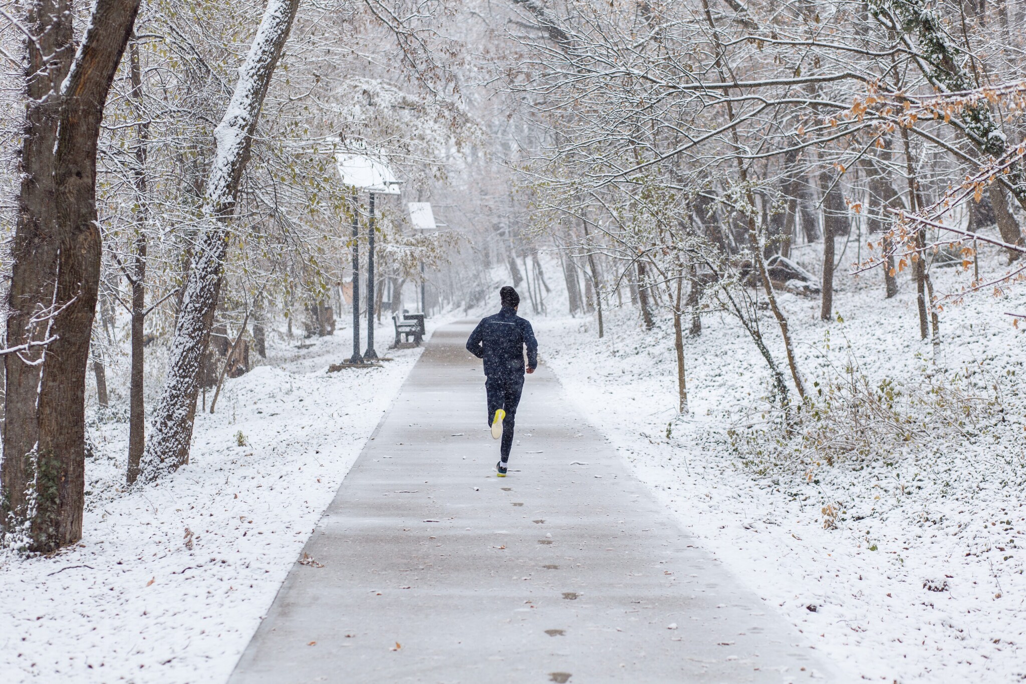 Mann von hinten fotografiert beim Joggen durch eine Winterlandschaft
