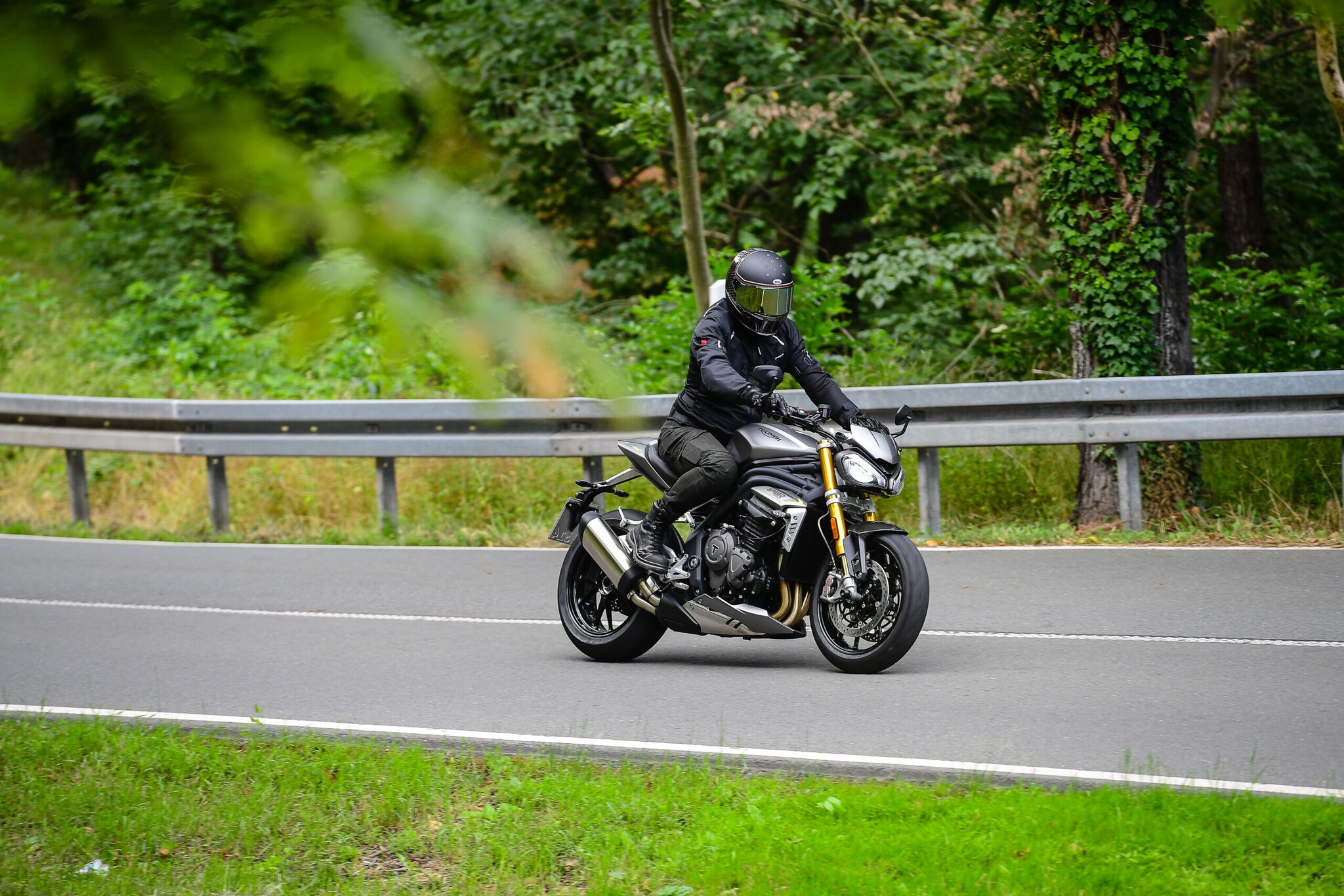 Ein silbergraues Motorrad mit einem Fahrer in schwarzer Kleidung auf der Landstraße Ein silbergraues Motorrad mit einem Fahrer in schwarzer Kleidung auf der Landstraße