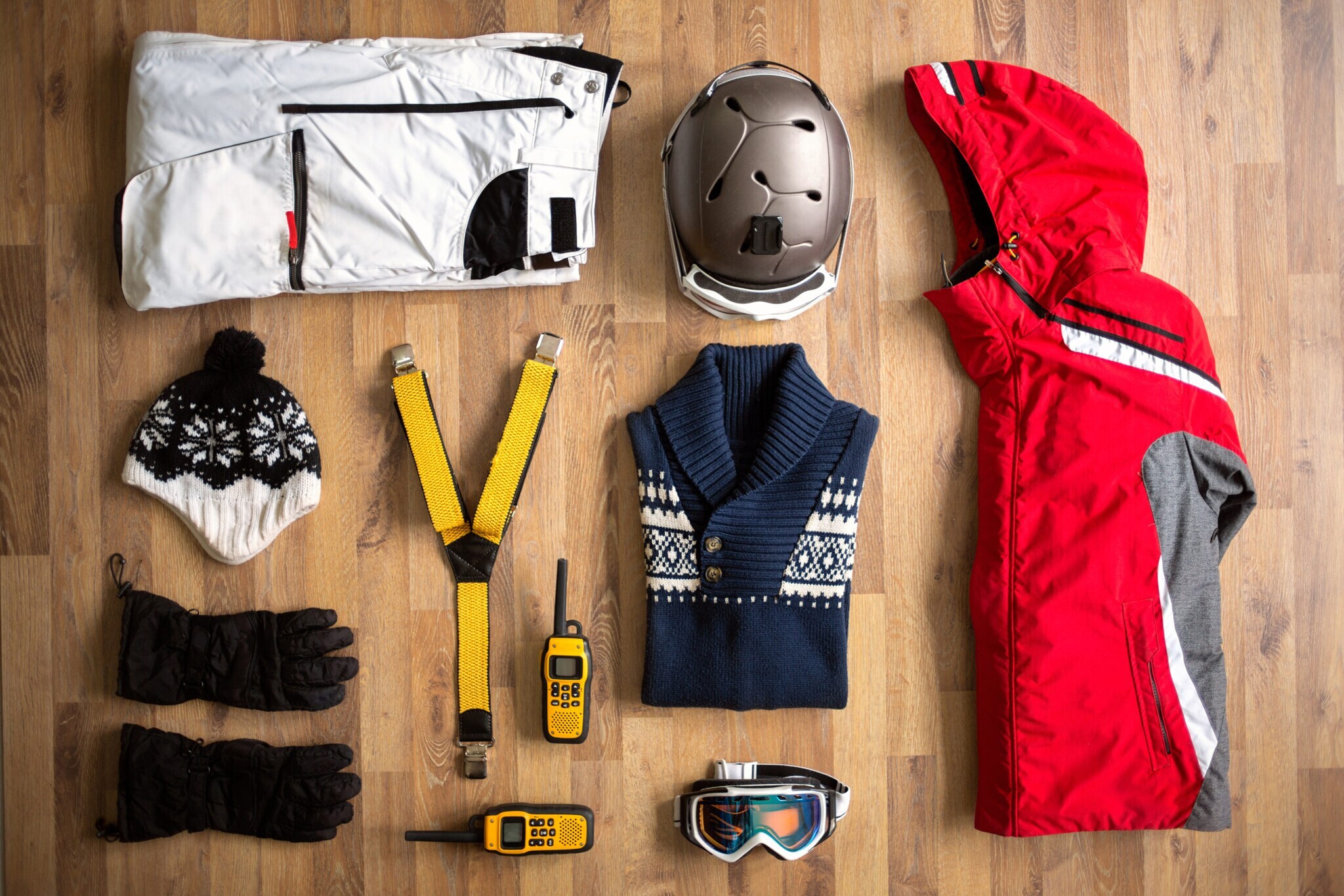 Handschuhe, Mütze, Jacke, Pullover, Helm, Hose, Skibrille und GPS-Gerät liegen auf dem Boden