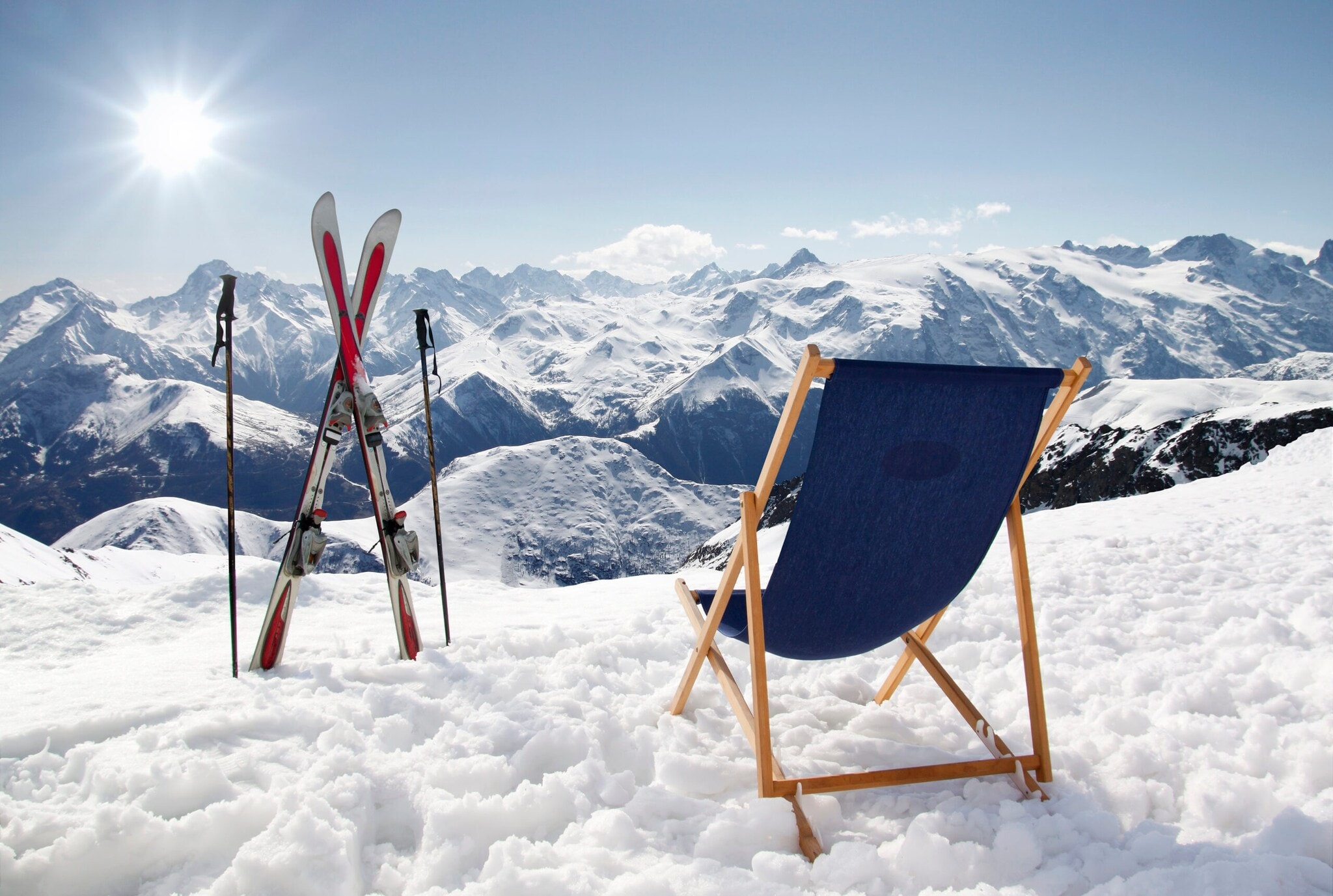 Ein Liegestuhl und Ski mit Stöcken auf einem Berg im Schnee Ein Liegestuhl und Ski mit Stöcken auf einem Berg im Schnee