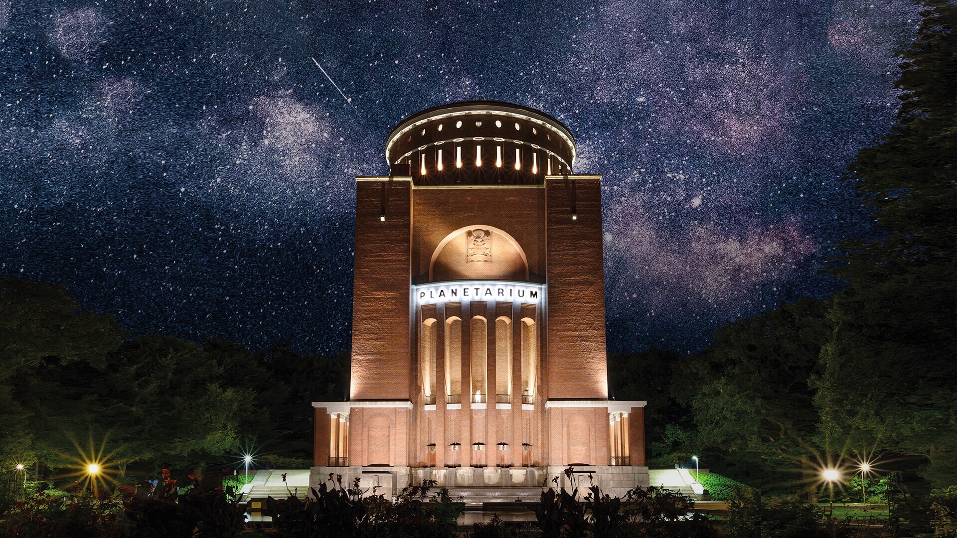 Das angeleuchtete Hamburger Planetarium, im Hintergrund ein Sternenhimmel