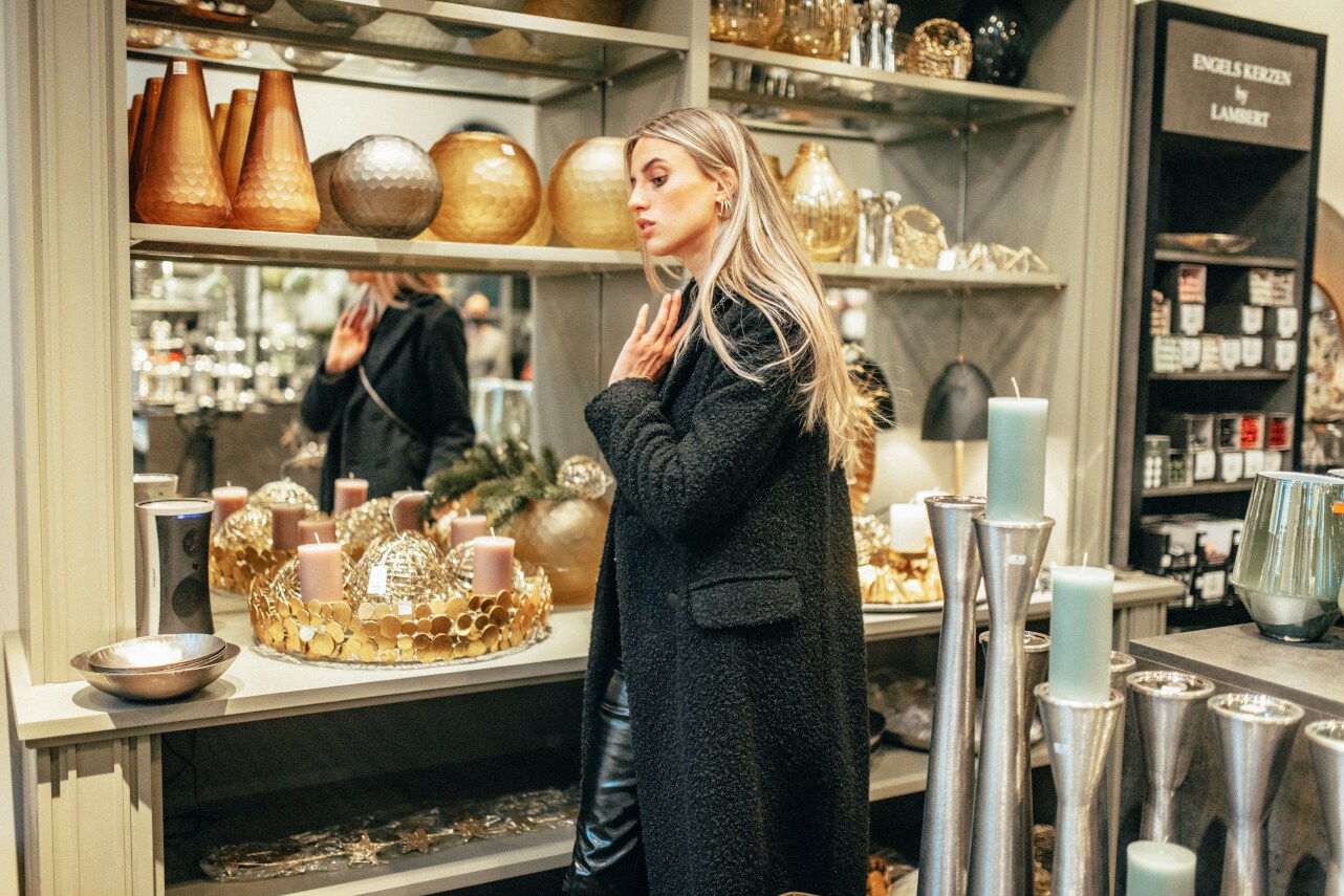 Eine schwarz gekleidete Frau mit langen Haaren steht vor einem weihnachtlichen Interieurangebot Eine schwarz gekleidete Frau mit langen Haaren steht vor einem weihnachtlichen Interieurangebot