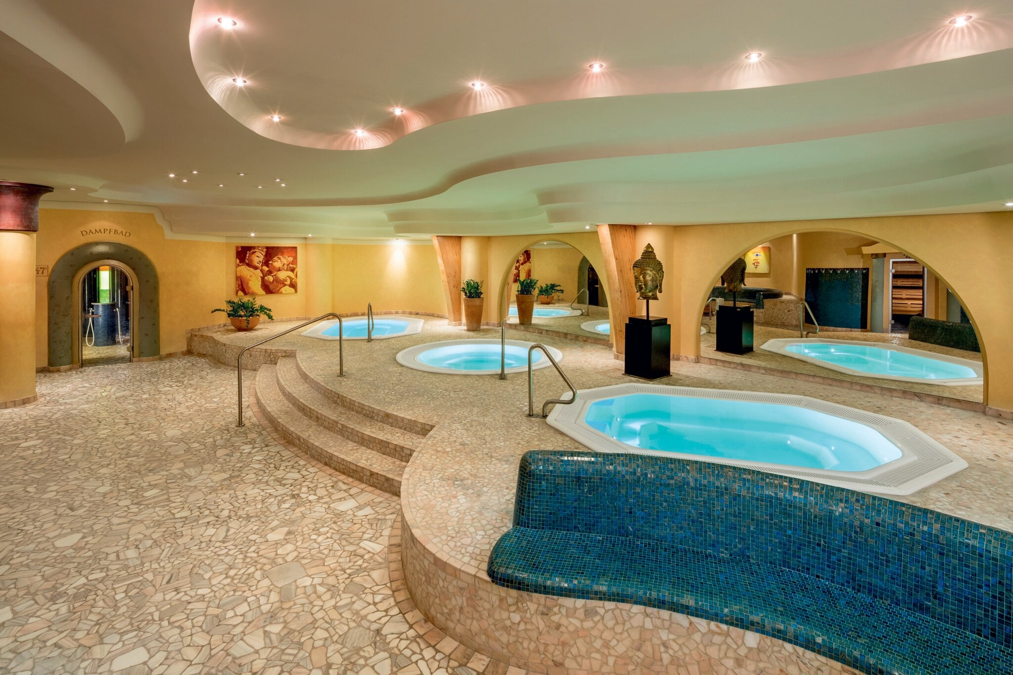 Drei Whirlpools in einer geschwungenen Saunalandschaft mit Mosaikfliesen