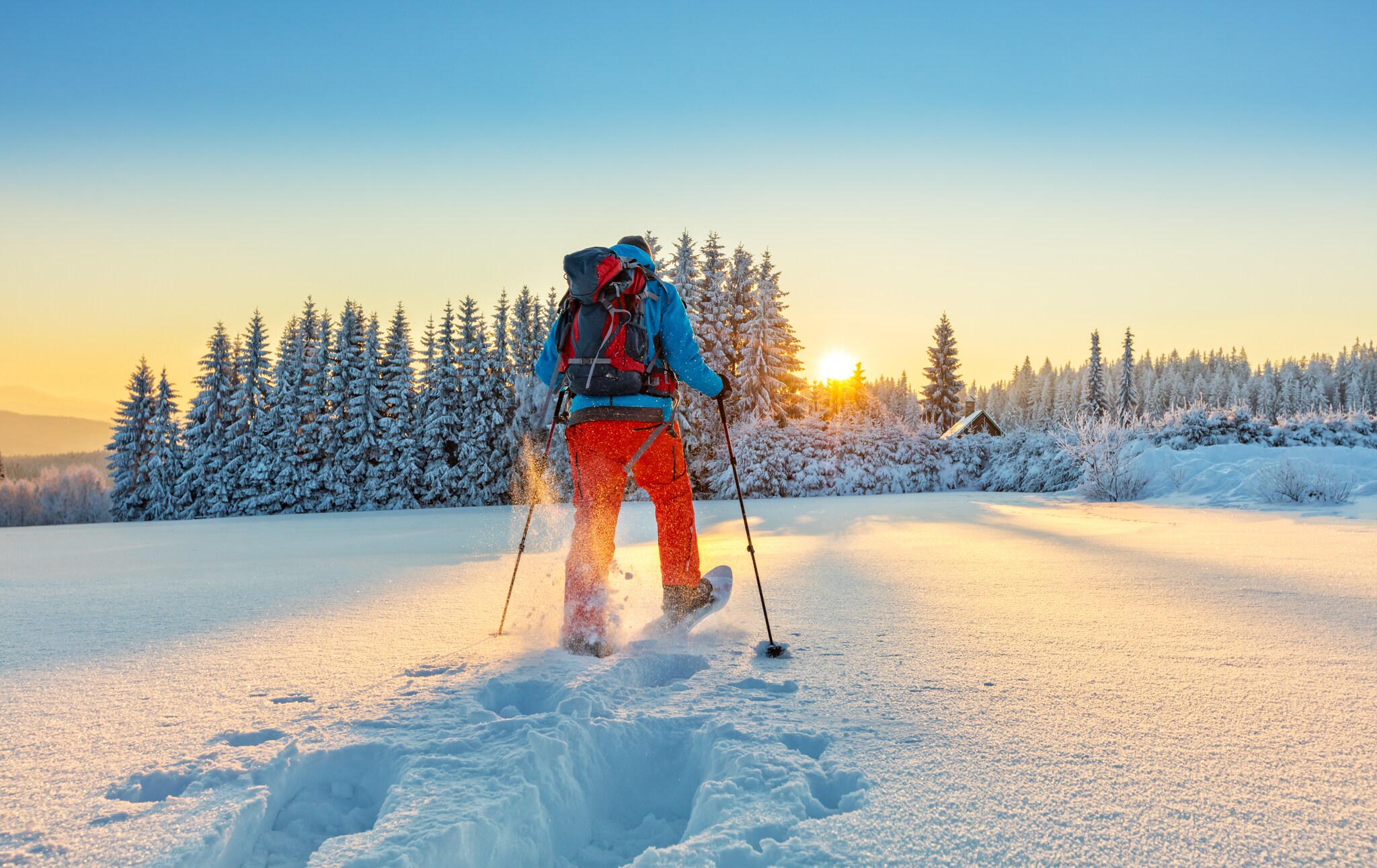 Mann von hinten beim Wandern durch eine Winterlandschaft Mann von hinten beim Wandern durch eine Winterlandschaft
