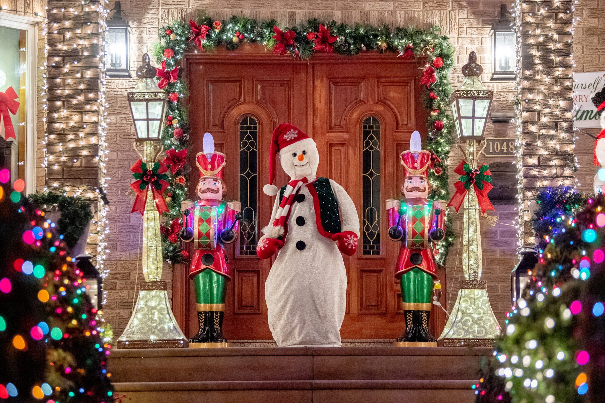 Ein weihnachtlich dekorierter und beleuchteter Hauseingang mit Schneemannfigur und Nussknackern