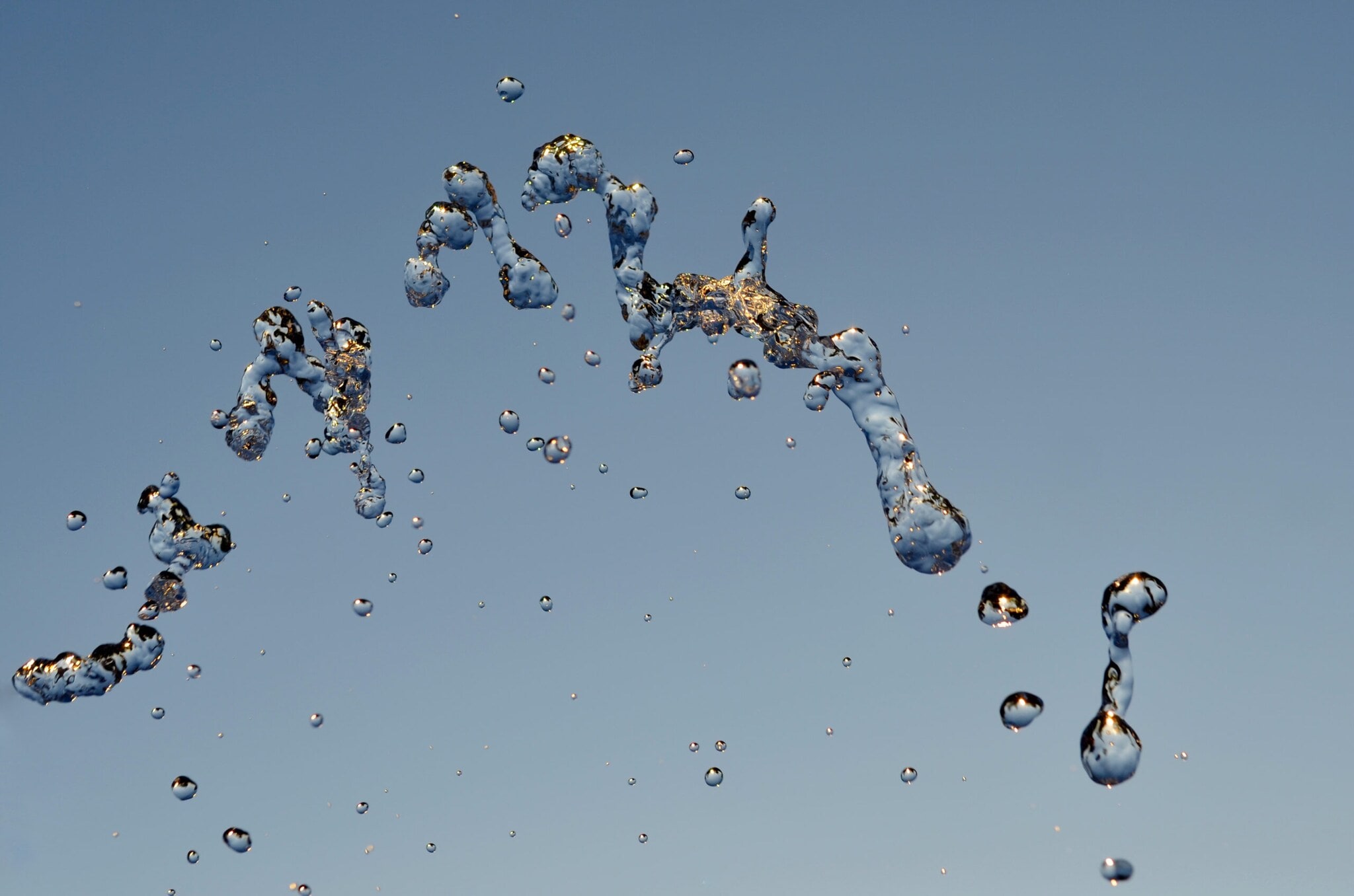 In der Luft hängende Wassertropfen vor blauem Hintergrund. In der Luft hängende Wassertropfen vor blauem Hintergrund.