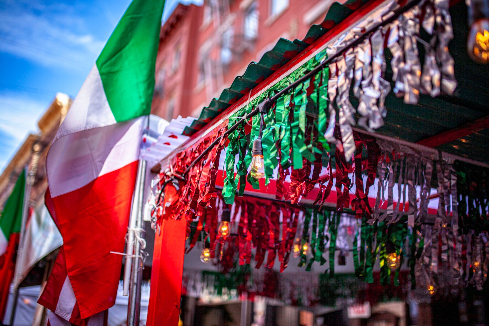Nahaufnahme von Girlanden und Fahnen in den italienischen Nationalfarben vor einer Hausfassade