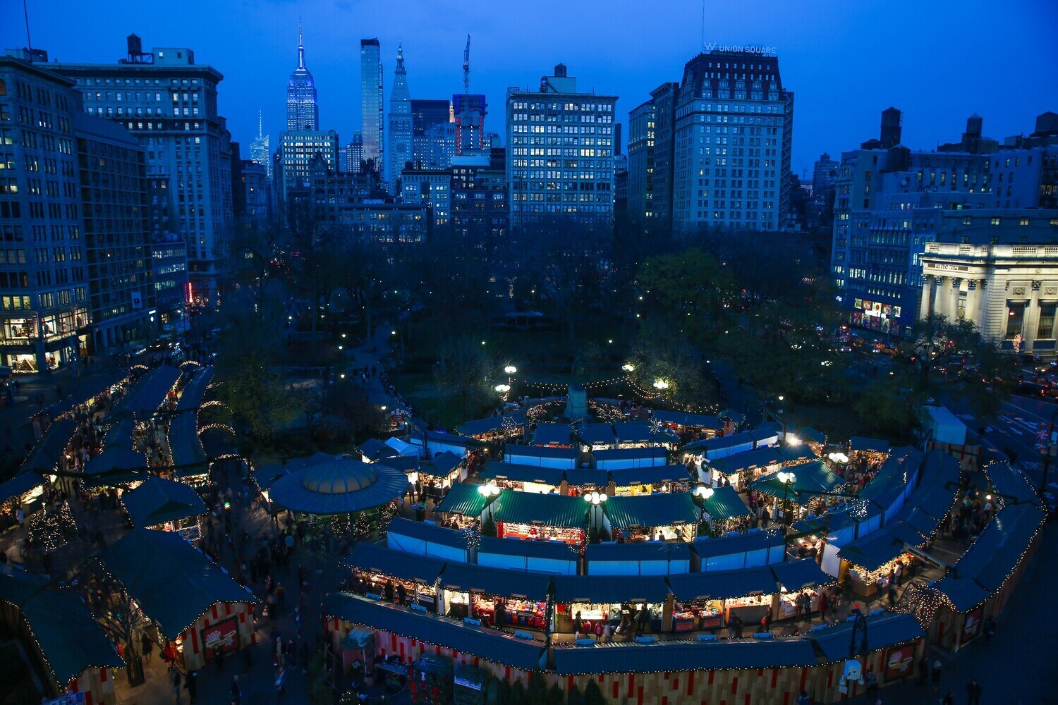 Blick aus der Höhe auf den Union Square mit beleuchteten Marktständen bei Dunkelheit