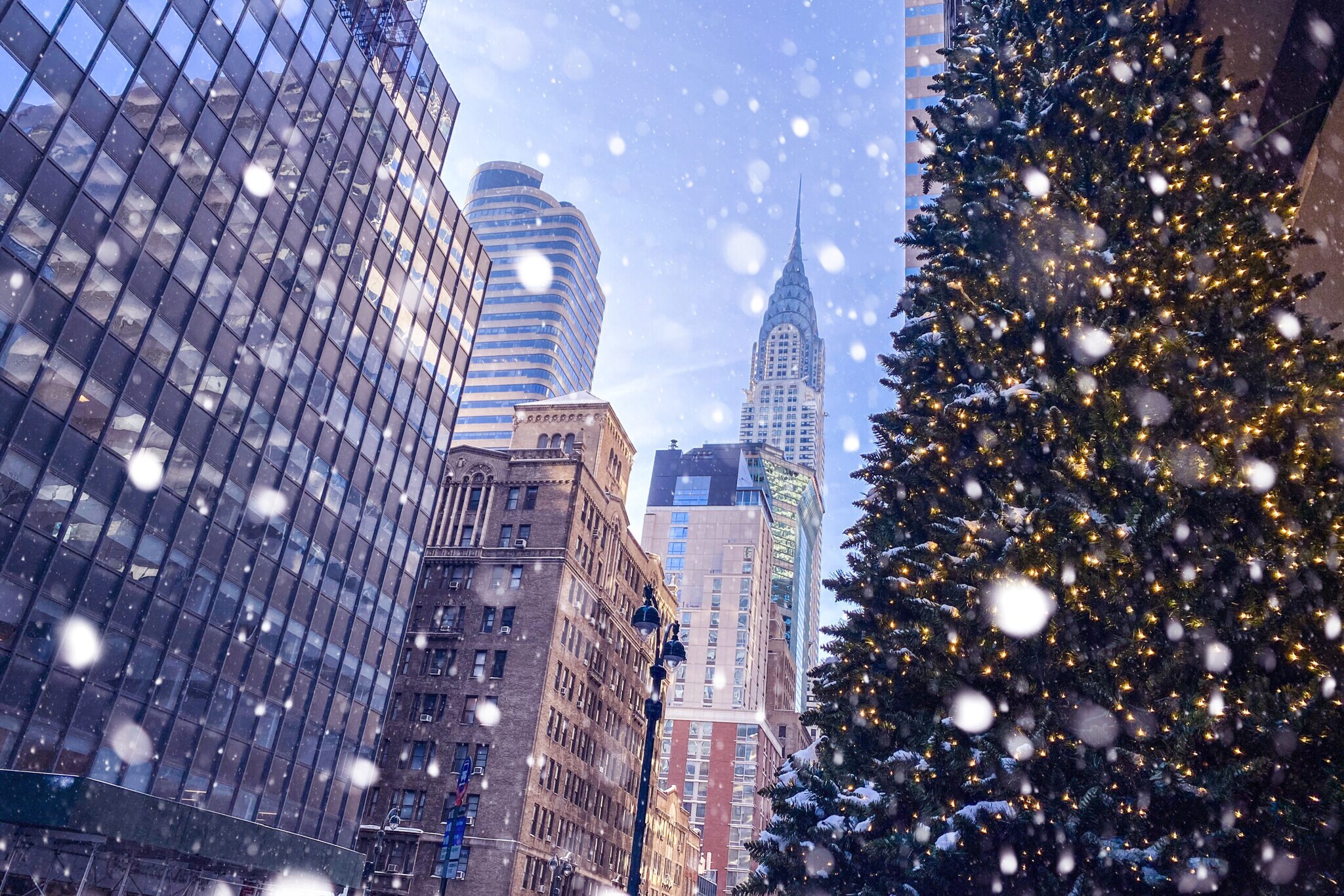 Häuserschlucht in Manhattan mit Blick auf Chrysler Building und Tannenbaum im Vordergrund bei Schneefall Häuserschlucht in Manhattan mit Blick auf Chrysler Building und Tannenbaum im Vordergrund bei Schneefall
