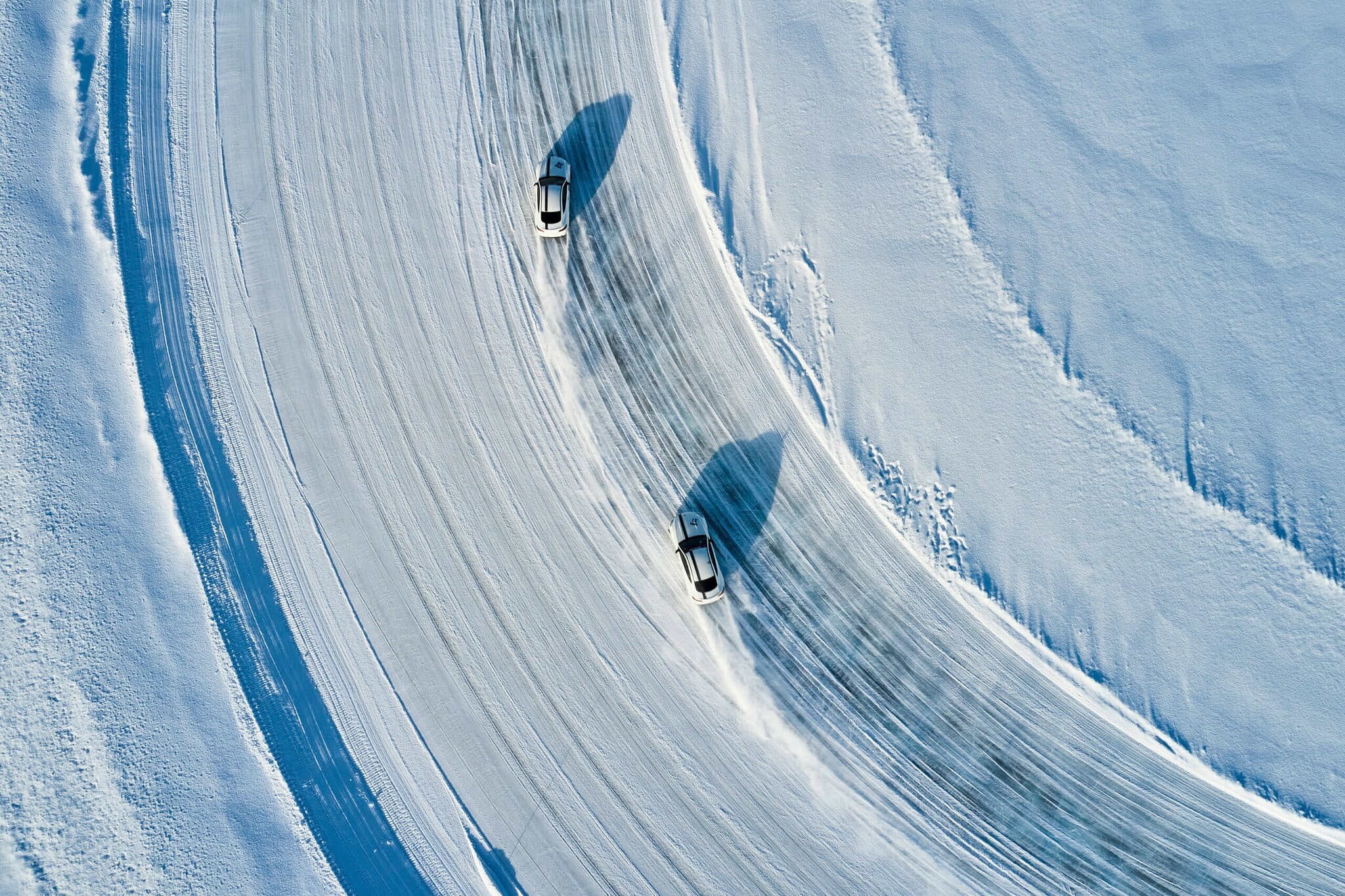 Zwei Sportwagen fahren über ein Eisfeld.