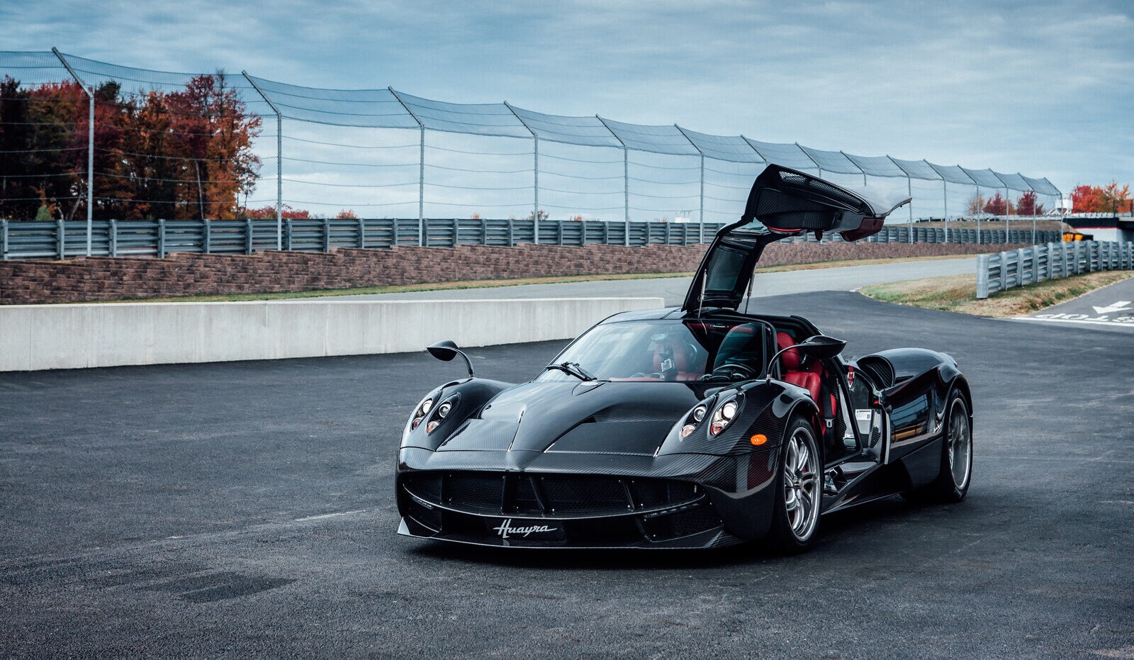 Der Sportwagen Pagani Huayra mit offener Flügeltür auf einer Rennstrecke.