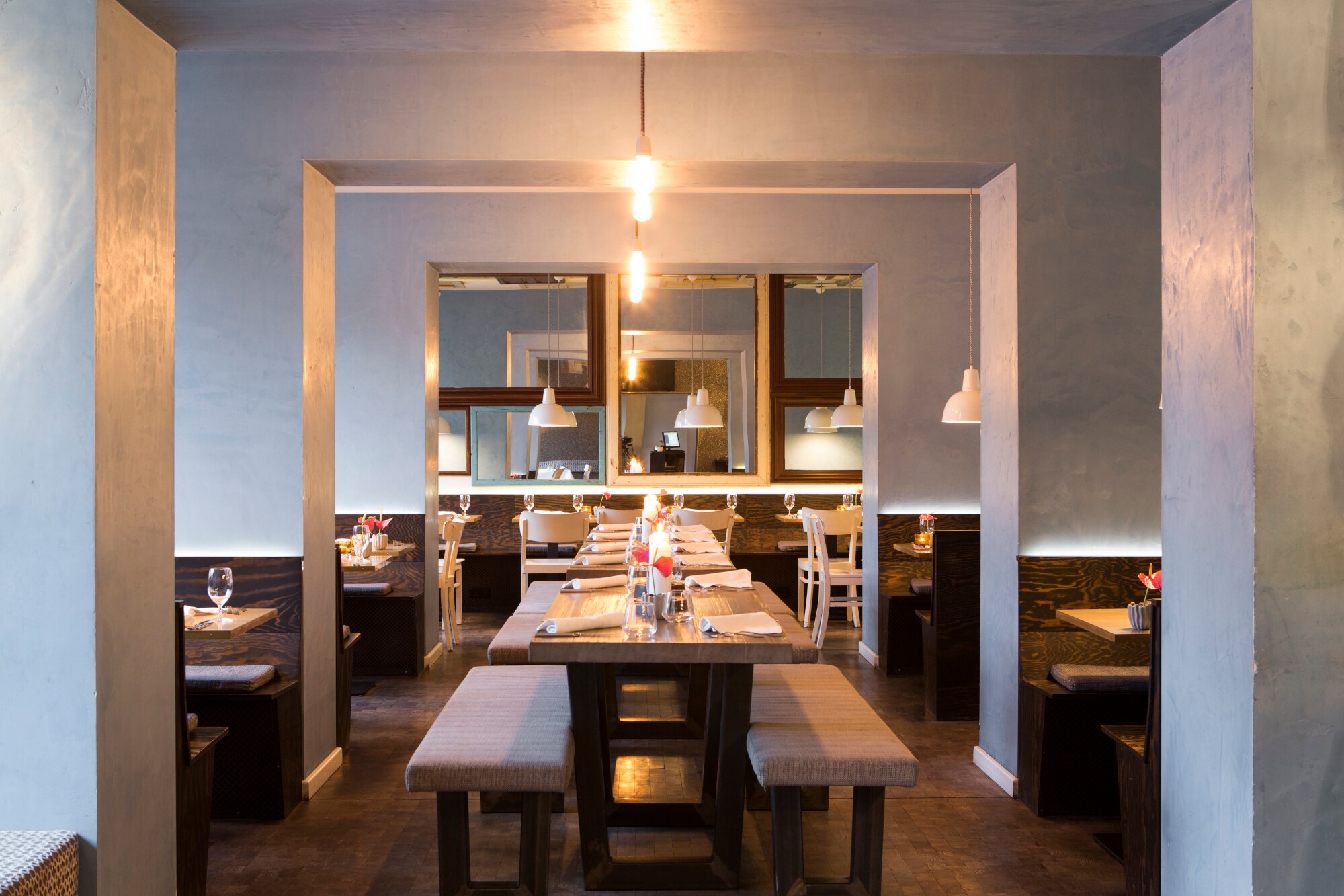 Innenaufnahme eines modernen Restaurants mit gedeckten Holztischen Innenaufnahme eines modernen Restaurants mit gedeckten Holztischen