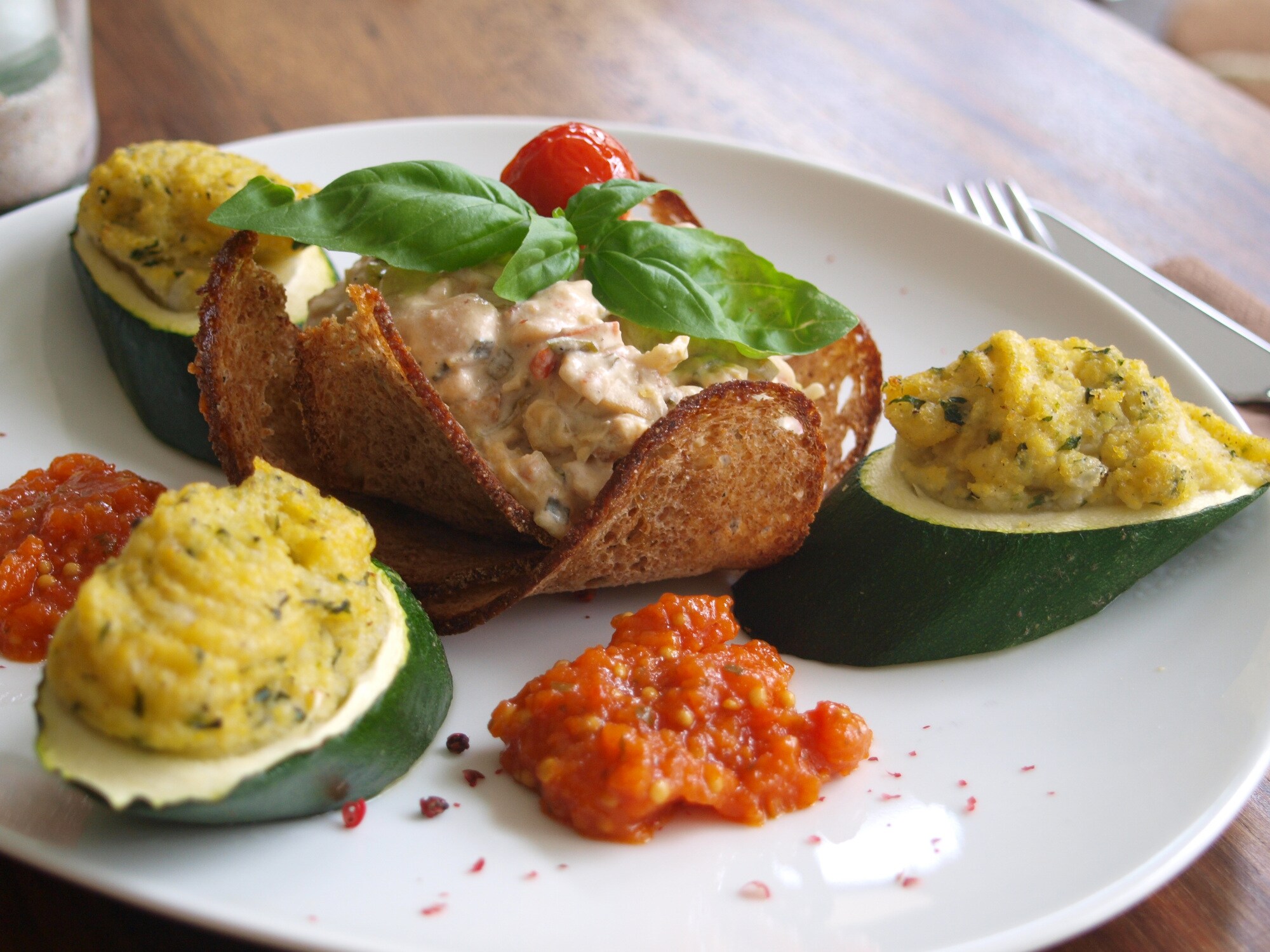 Nahaufnahme einer veganen Speise mit gefüllter Zucchini auf weißem Porzellanteller