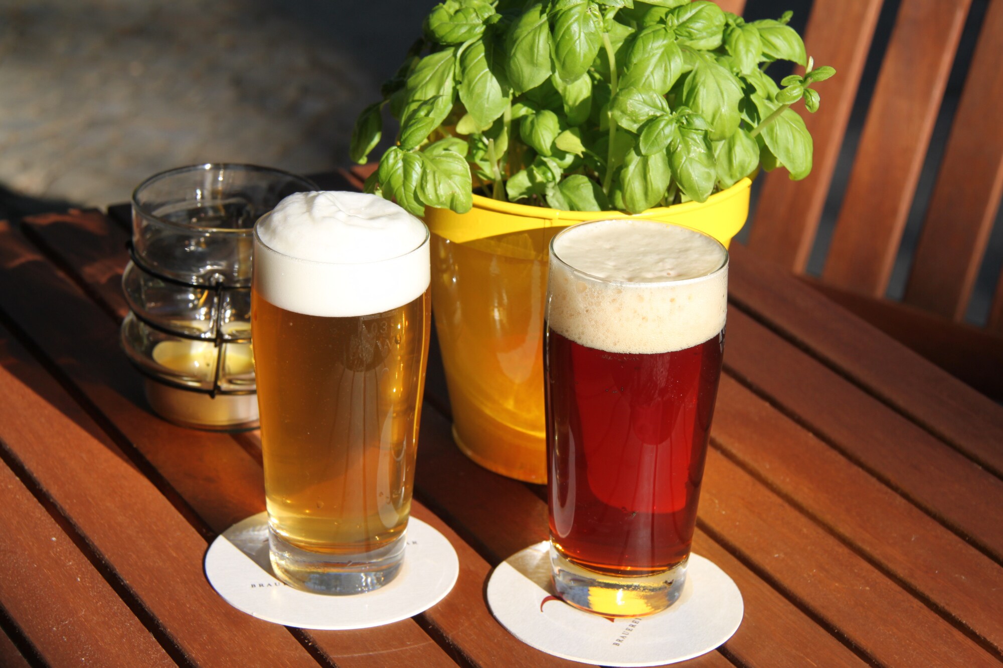 Ein dunkles und ein helles Bier in Gläsern stehen auf einem Gartentisch aus Holz Ein dunkles und ein helles Bier in Gläsern stehen auf einem Gartentisch aus Holz