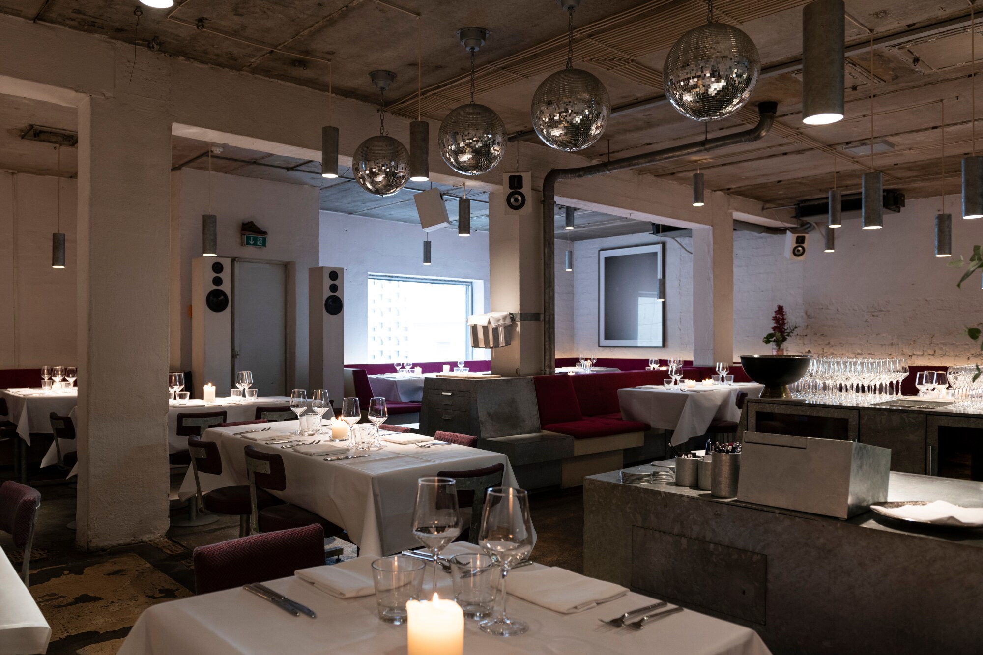 Innenraumaufnahme eines modernen Restaurants im Industrial-Stil mit elegant gedeckten Tischen Innenraumaufnahme eines modernen Restaurants im Industrial-Stil mit elegant gedeckten Tischen