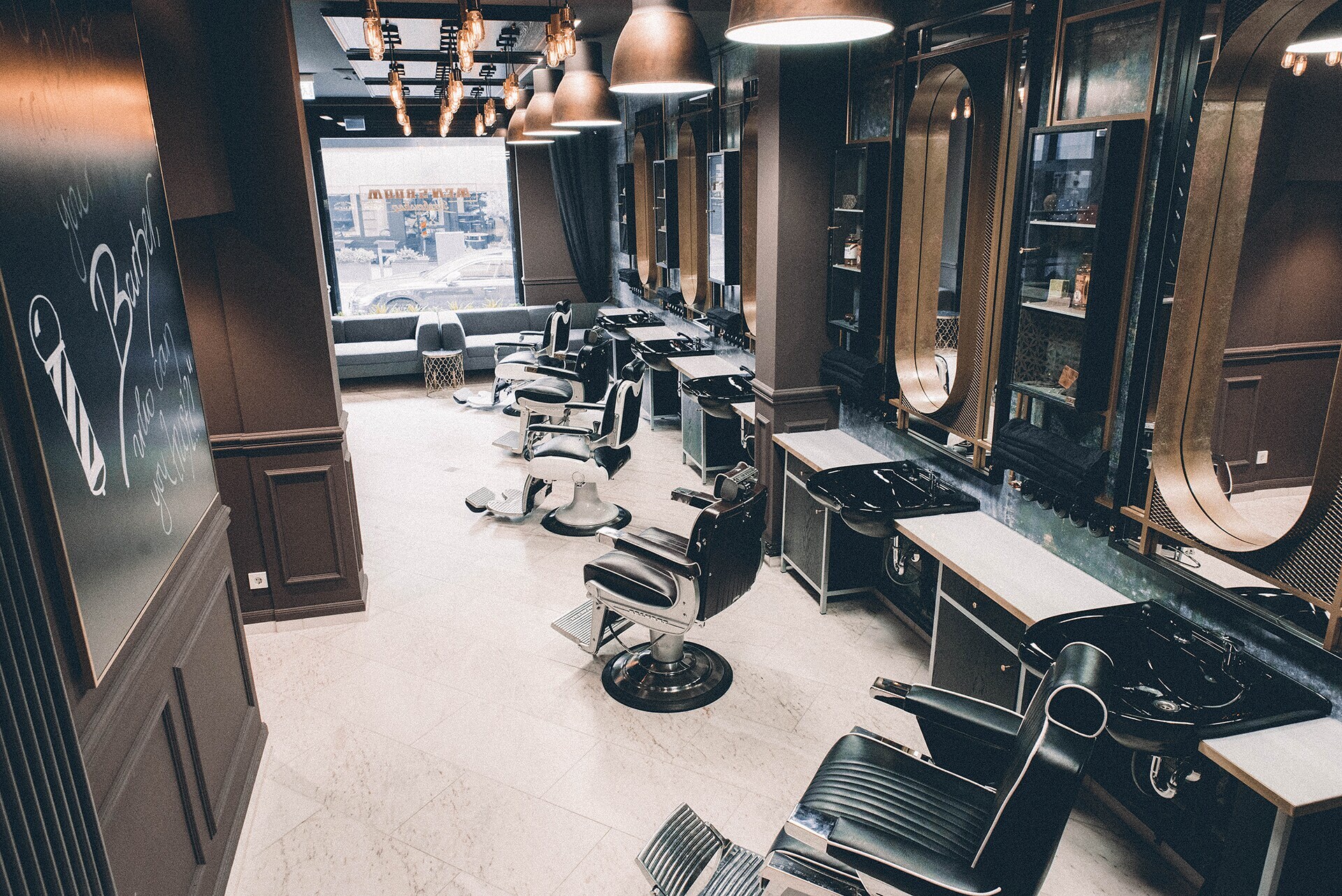 Das elegante Interieur eines Barbershops mit Friseursesseln, Waschbecken, schokoladenfarbenen Wänden und Messingelementen