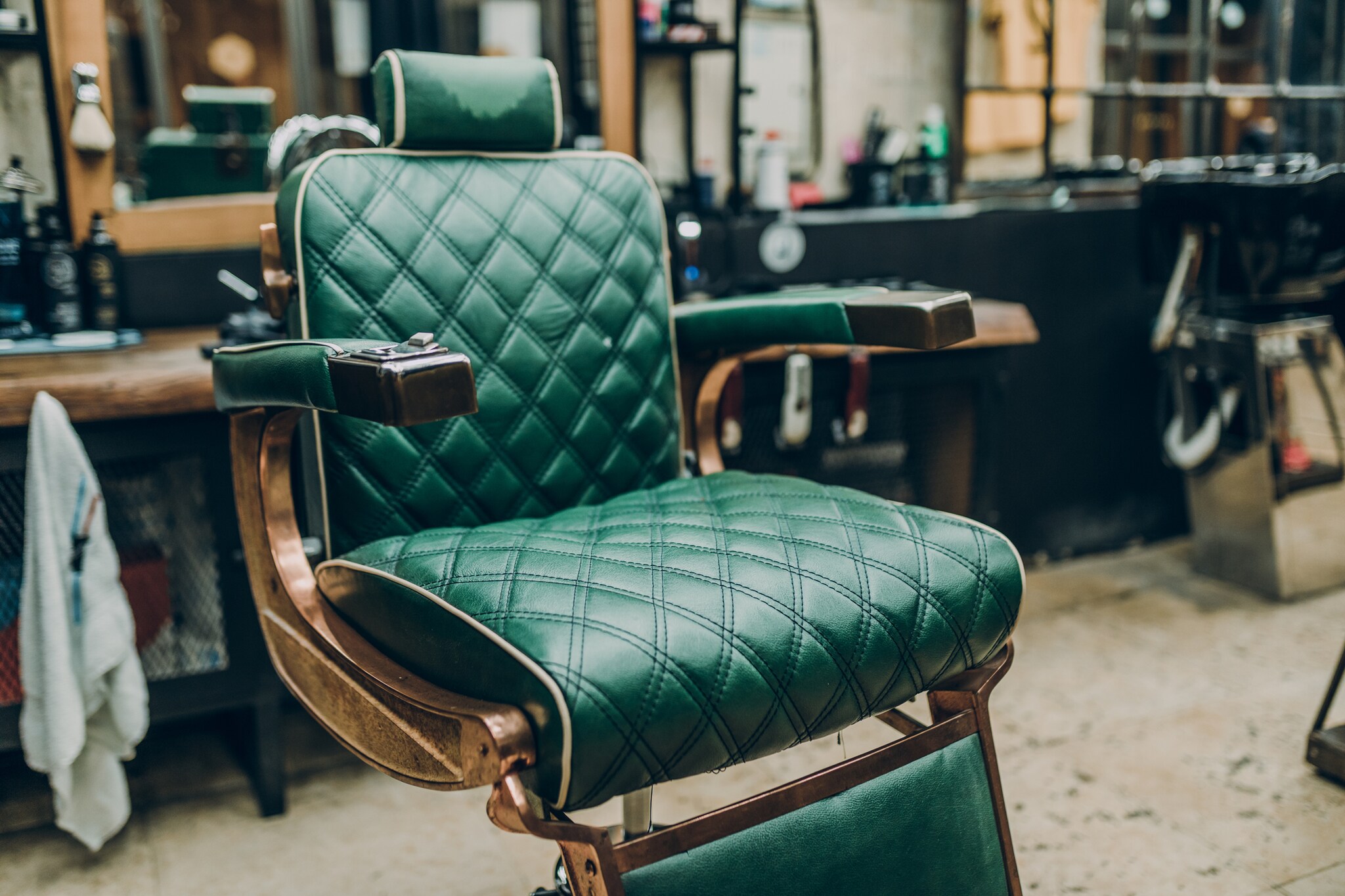 Ein Vintage-Barbersessel mit grünem Lederbezug in einem Barbershop
