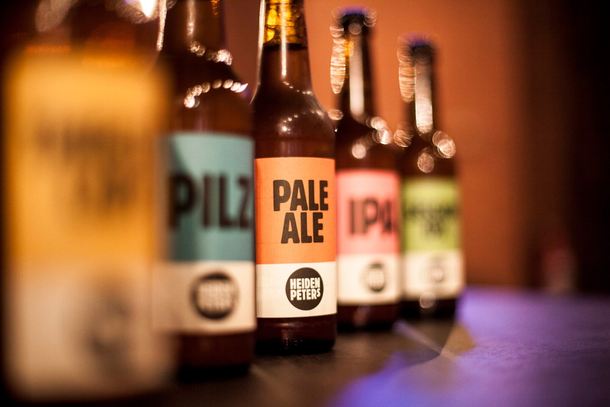 Bierflaschen mit bunten Etiketten aneinandergereiht Bierflaschen mit bunten Etiketten aneinandergereiht