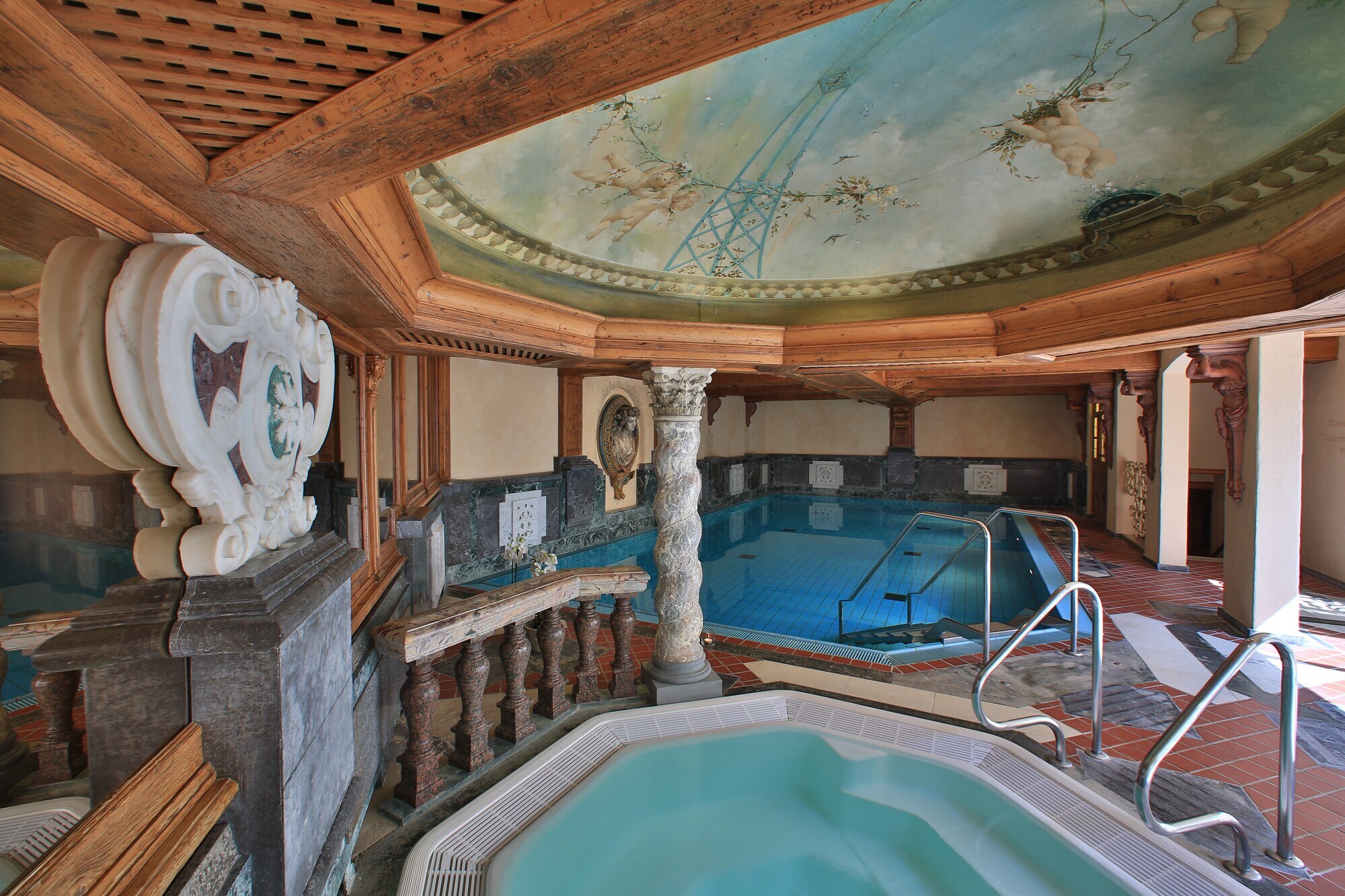 Schwimmbecken unter einer gewölbten Decke mit Deckenbemalung.