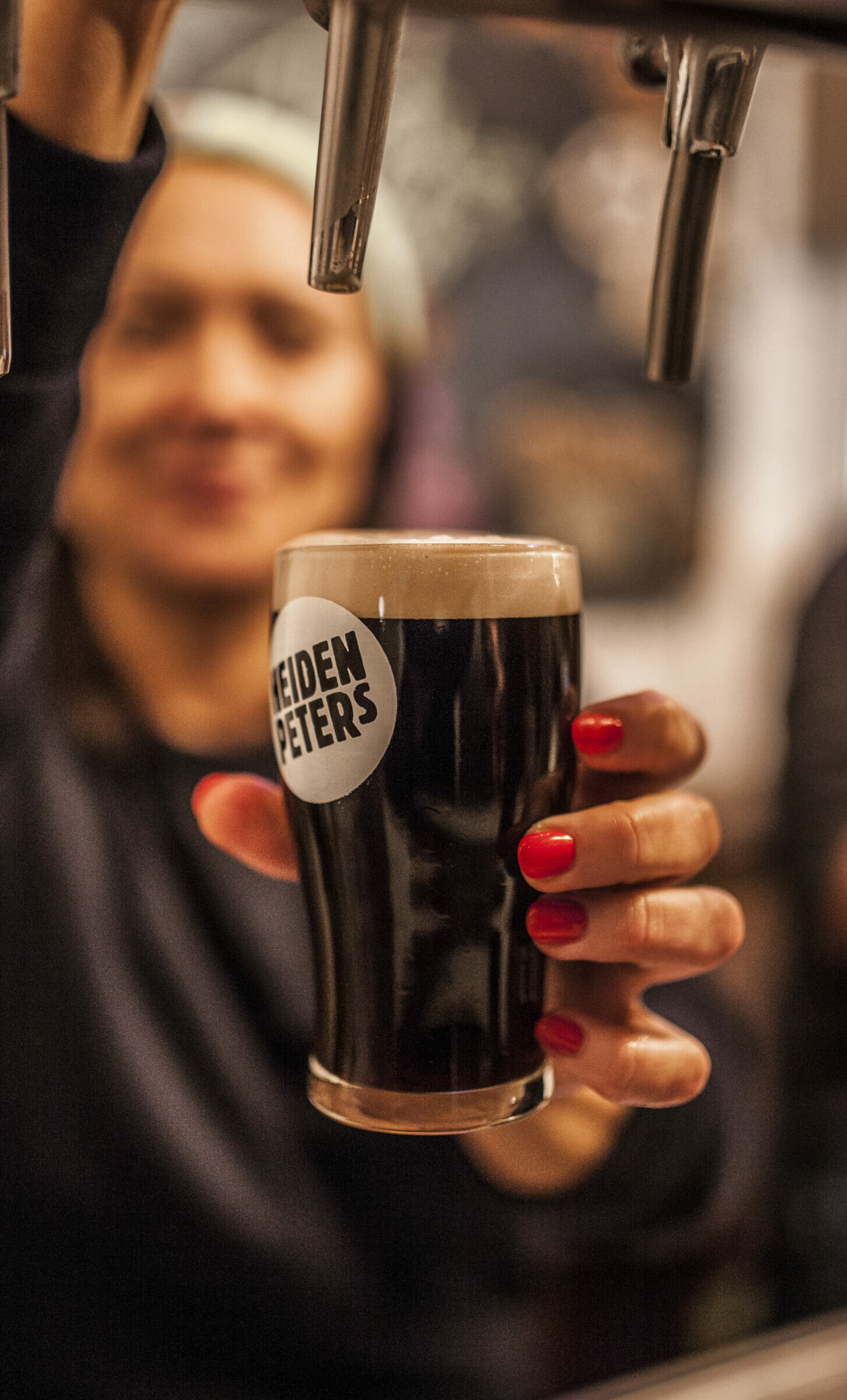 Eine Frau zapft ein dunkles Bier an einem Zapfhahn Eine Frau zapft ein dunkles Bier an einem Zapfhahn
