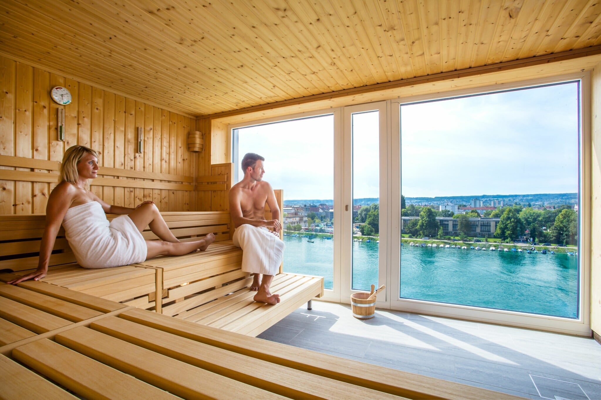 Zwei Saunagäste blicken durch ein Panoramafenster. Zwei Saunagäste blicken durch ein Panoramafenster.
