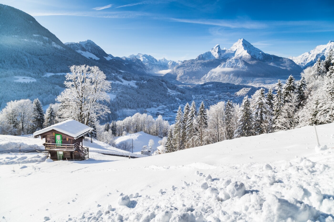 Eine schneebedeckte Berglandschaft, im Vordergrund steht eine kleine Holzhütte Eine schneebedeckte Berglandschaft, im Vordergrund steht eine kleine Holzhütte
