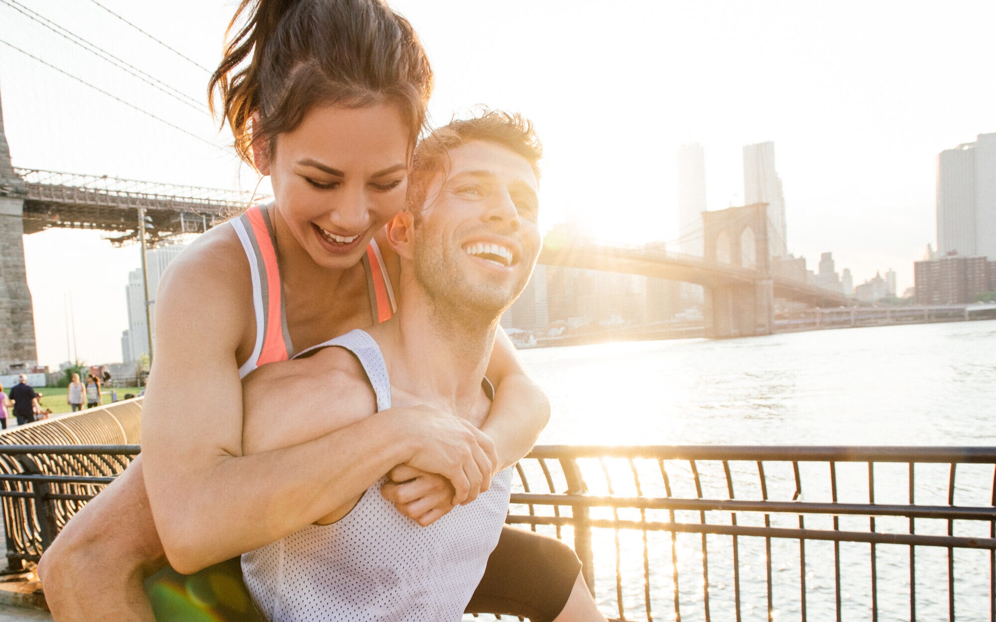 Ein Mann trägt eine Frau auf dem Rücken, im Hintergrund die Brooklyn Bridge Ein Mann trägt eine Frau auf dem Rücken, im Hintergrund die Brooklyn Bridge
