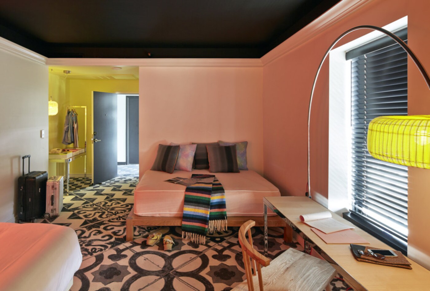 Modernes, geradliniges Hotelzimmer mit farbigen Wänden und Accessoires sowie einem gemusterten Teppichboden Modernes, geradliniges Hotelzimmer mit farbigen Wänden und Accessoires sowie einem gemusterten Teppichboden