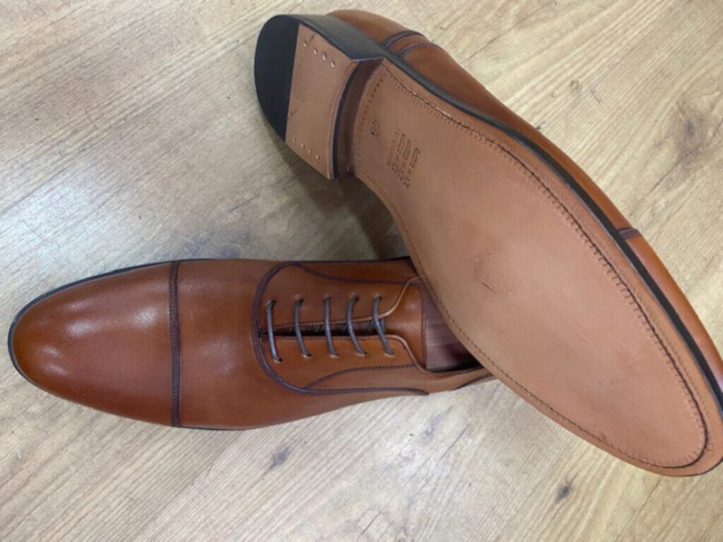 Brauner Männerschuh mit schwarzen Lederschnürsenkeln.