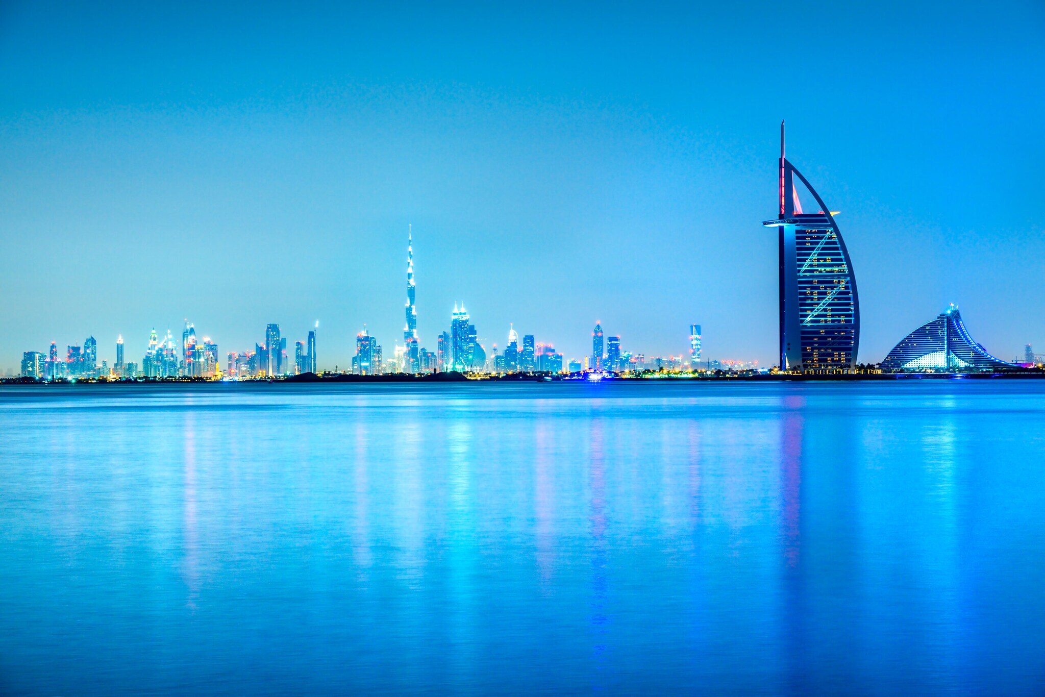 Skyline von Dubai mit Wasser im Vordergrund am Abend