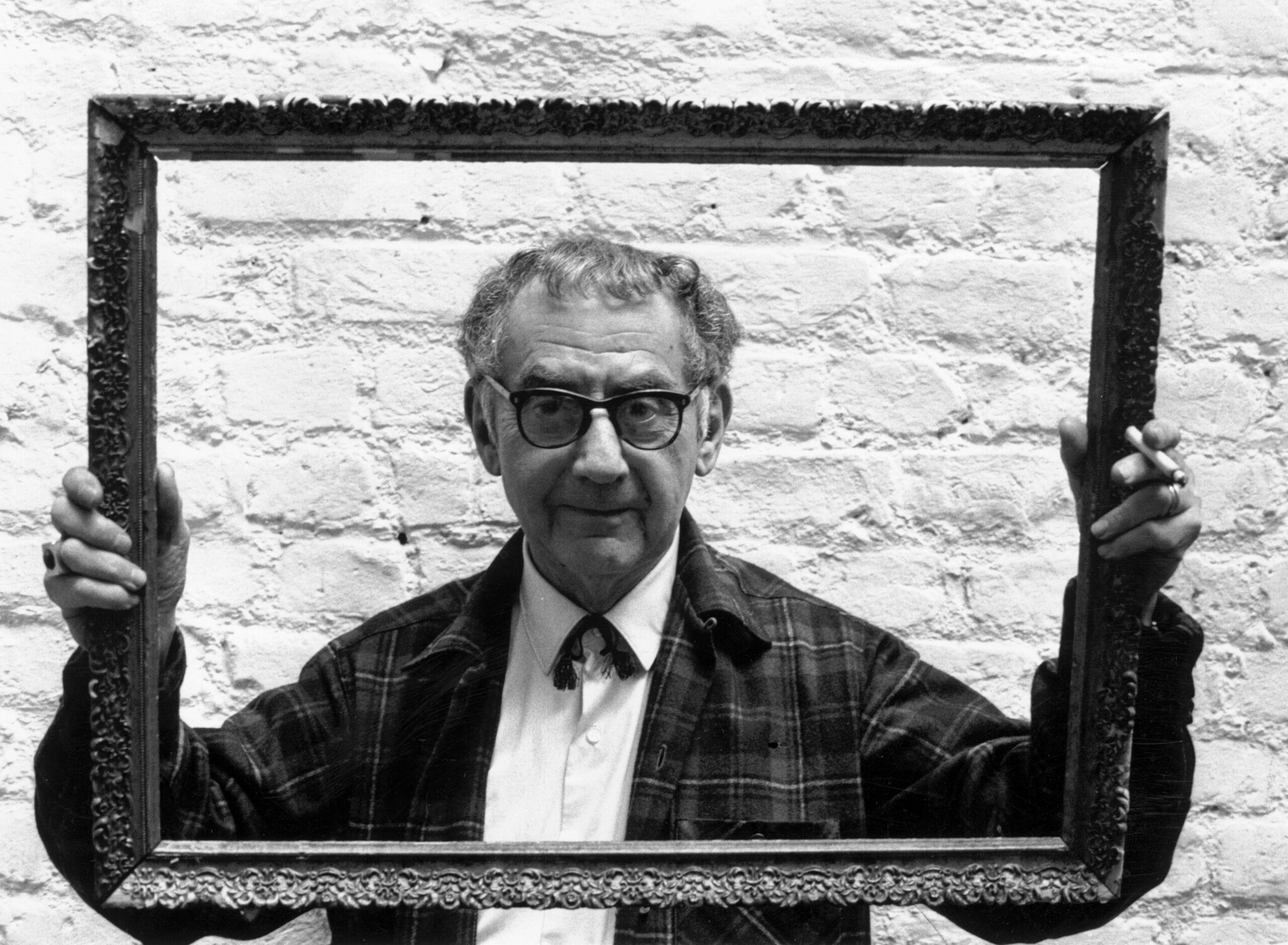 Fotograf Man Ray schaut durch einen Bilderrahmen Fotograf Man Ray schaut durch einen Bilderrahmen