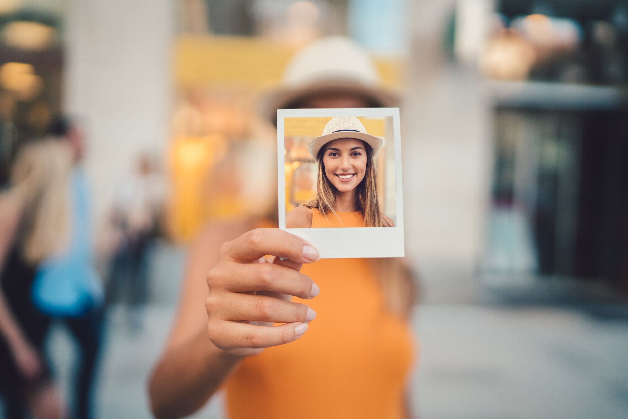 Eine junge Frau hält ein Polaroid in der Hand mit einem Selbstportrait