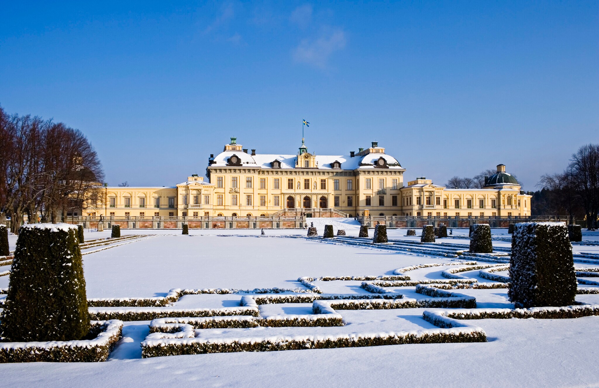 Das eingeschneite Schloss Drottningholm mit seinem Schlossgarten bei Sonnenschein