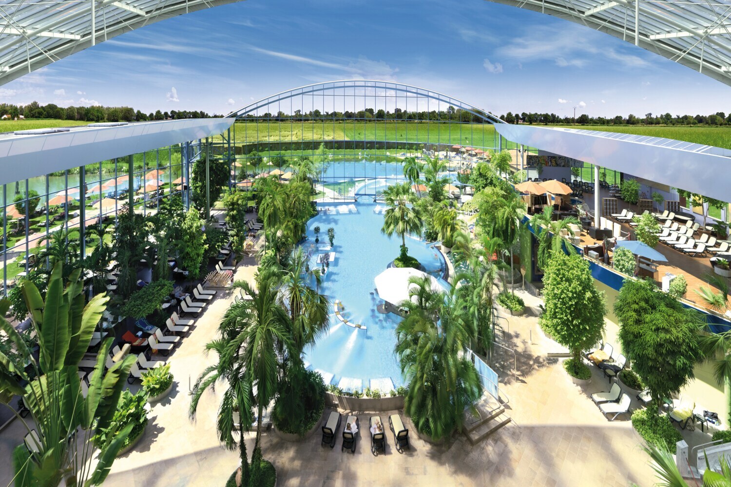 Panoramasicht auf eine große Badelandschaft mit einem großem Schwimmbecken und tropischen Pflanzen unter einer geöffneten Kuppel, die den Blick auf den blauen Himmel freigibt Panoramasicht auf eine große Badelandschaft mit einem großem Schwimmbecken und tropischen Pflanzen unter einer geöffneten Kuppel, die den Blick auf den blauen Himmel freigibt