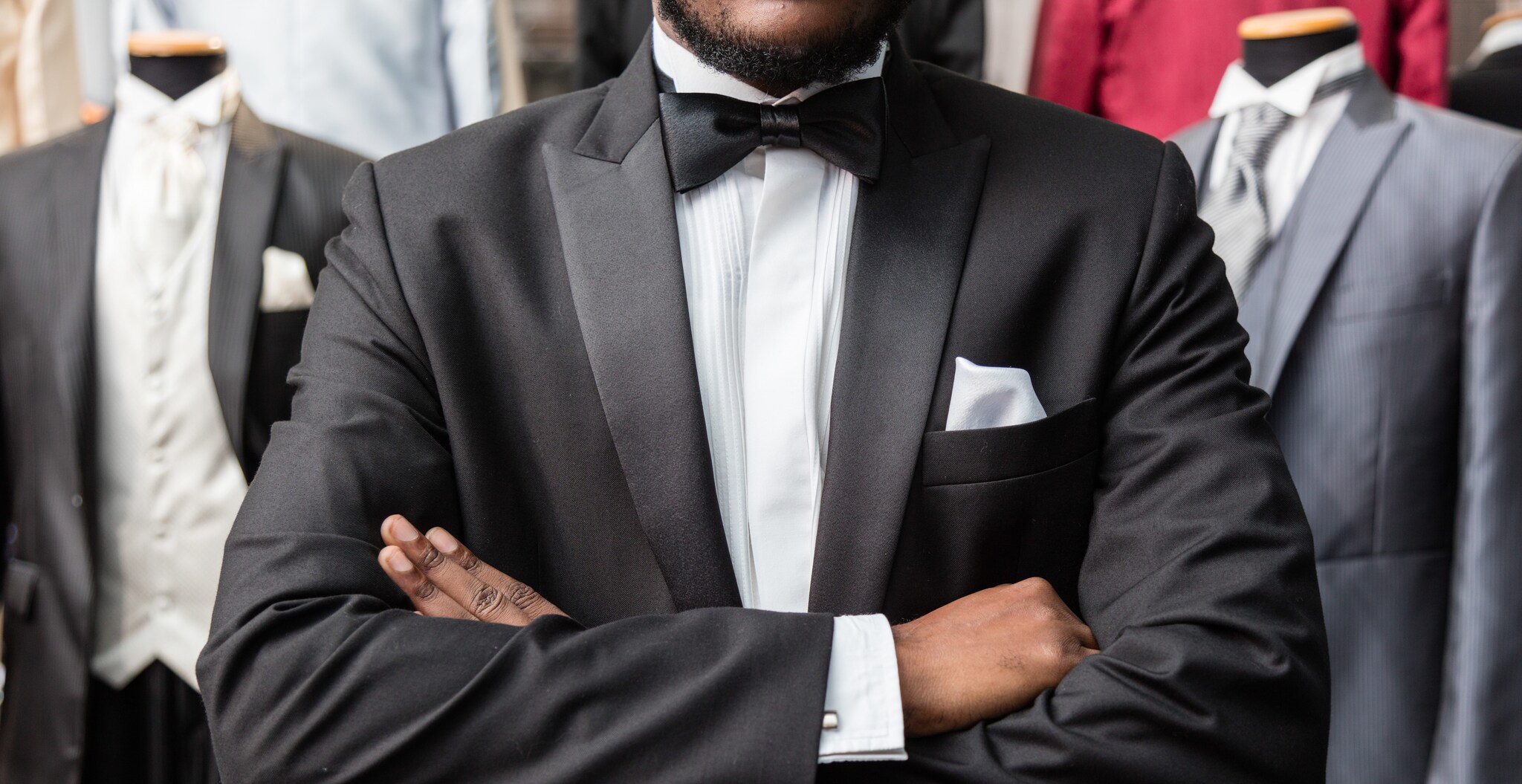 Ein Mann, der Smoking und Fliege trägt, verschränkt die Arme vor der Brust