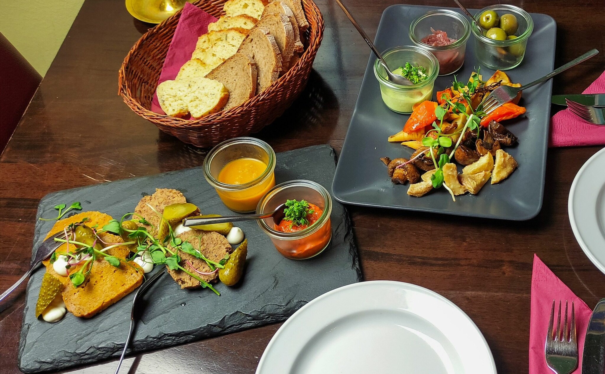 Verschiedene vegetarische Tapas mit Dips und einem Brotkorb auf einem gedeckten Restauranttisch Verschiedene vegetarische Tapas mit Dips und einem Brotkorb auf einem gedeckten Restauranttisch