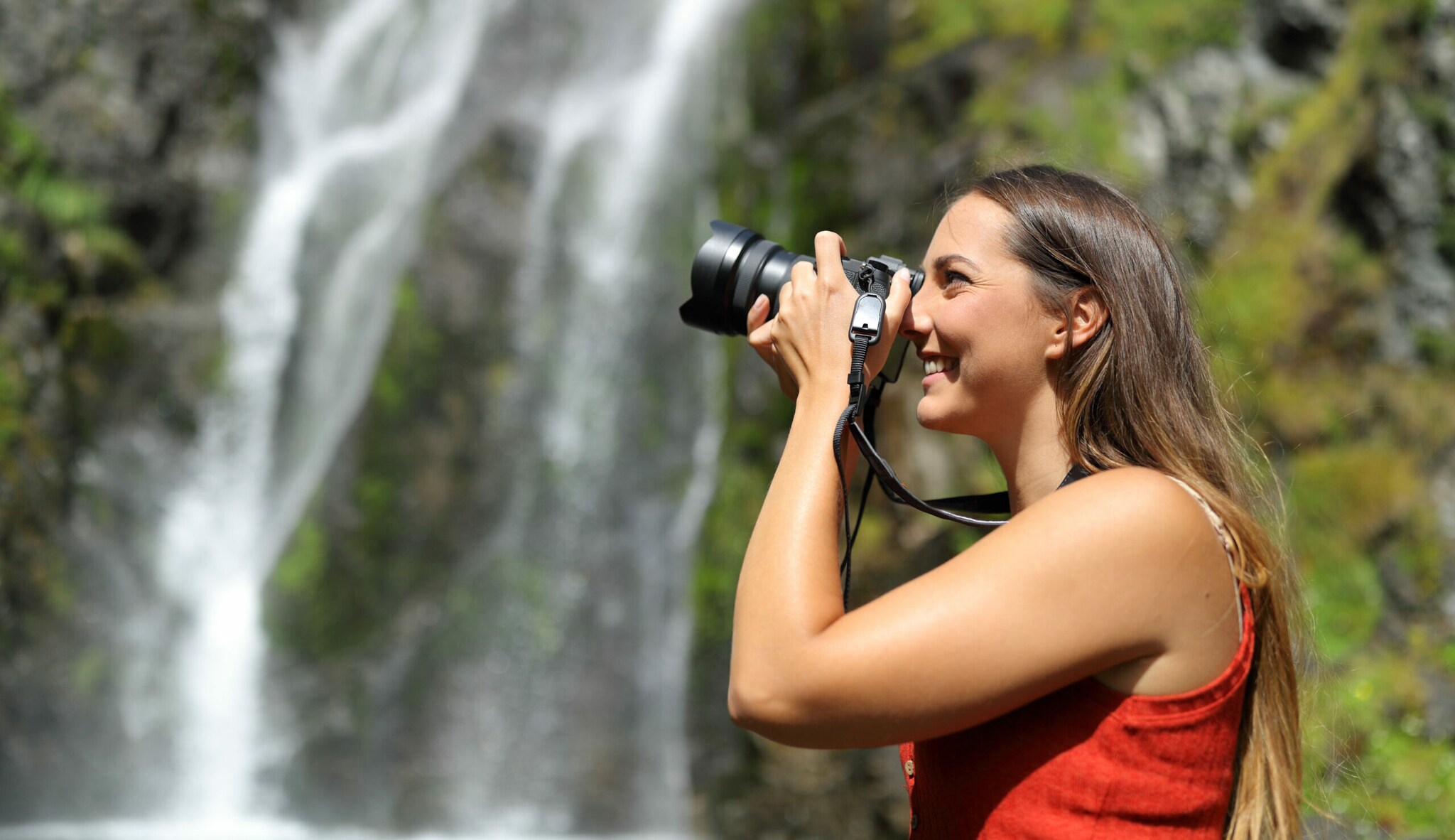 Eine junge Frau fotografiert einen Wasserfall.
