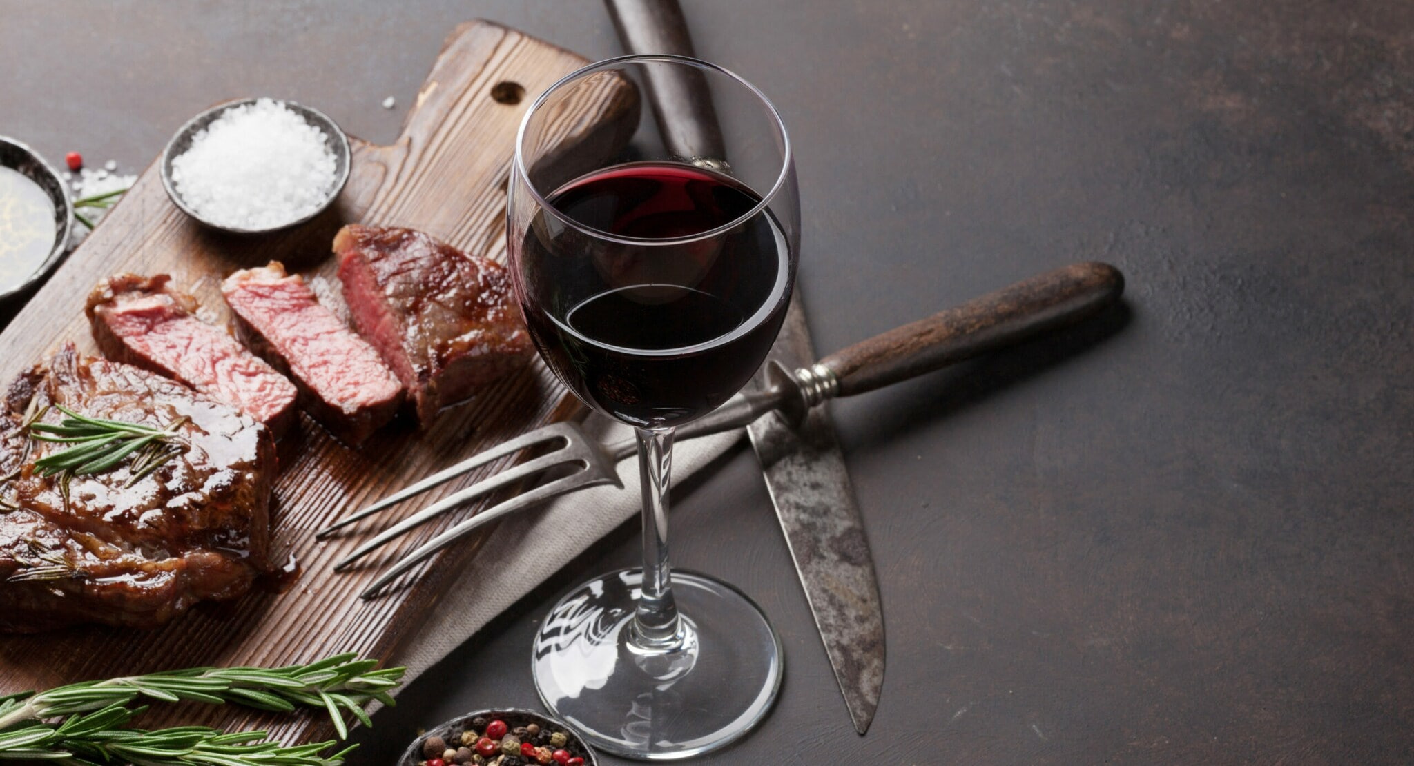 Ein Glas Rotwein neben einem Brett mit Fleisch. Ein Glas Rotwein neben einem Brett mit Fleisch.