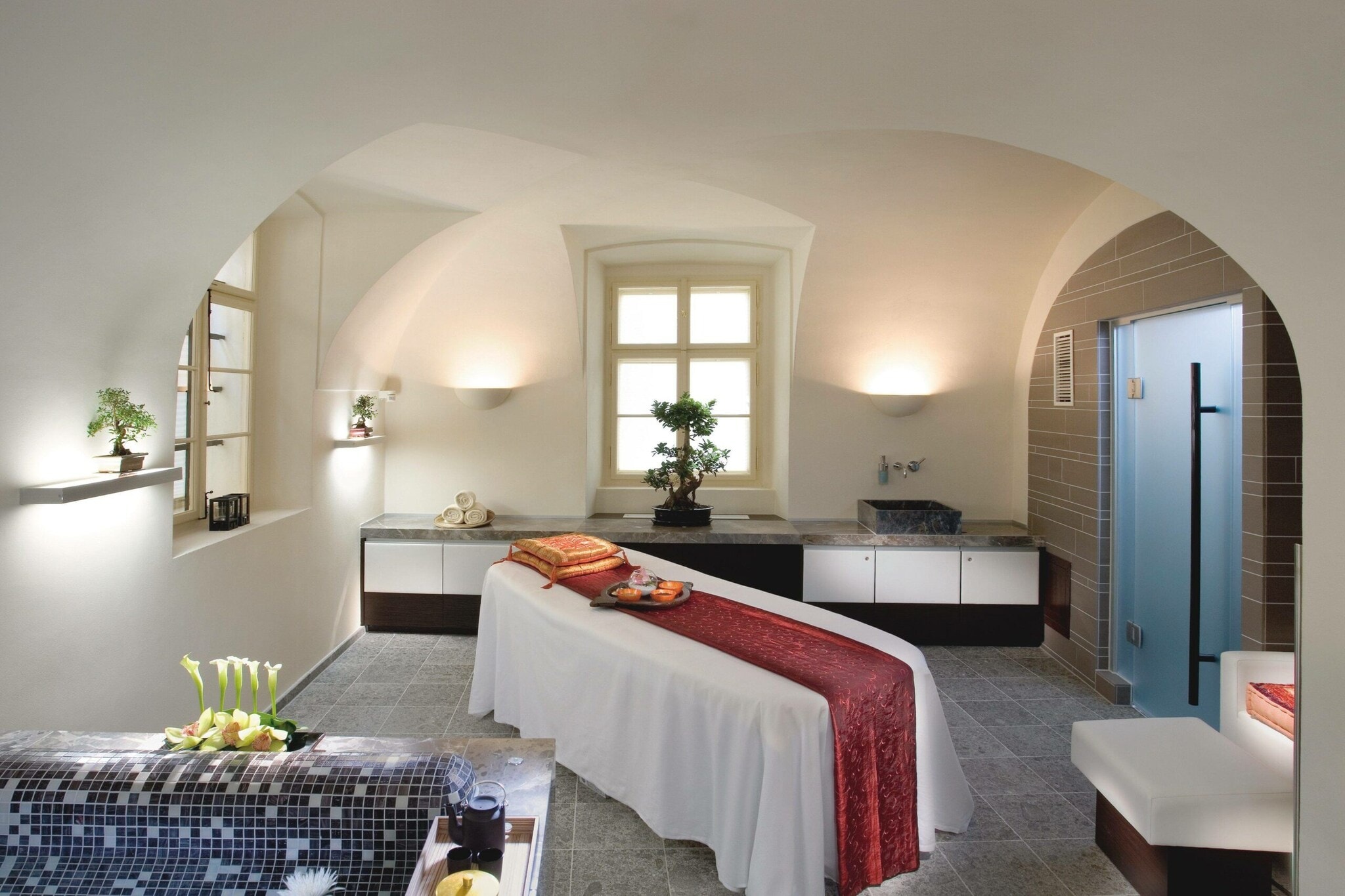 Innenansicht eines Raumes mit Massageliege, Möbeln und Zimmerpflanzen Innenansicht eines Raumes mit Massageliege, Möbeln und Zimmerpflanzen