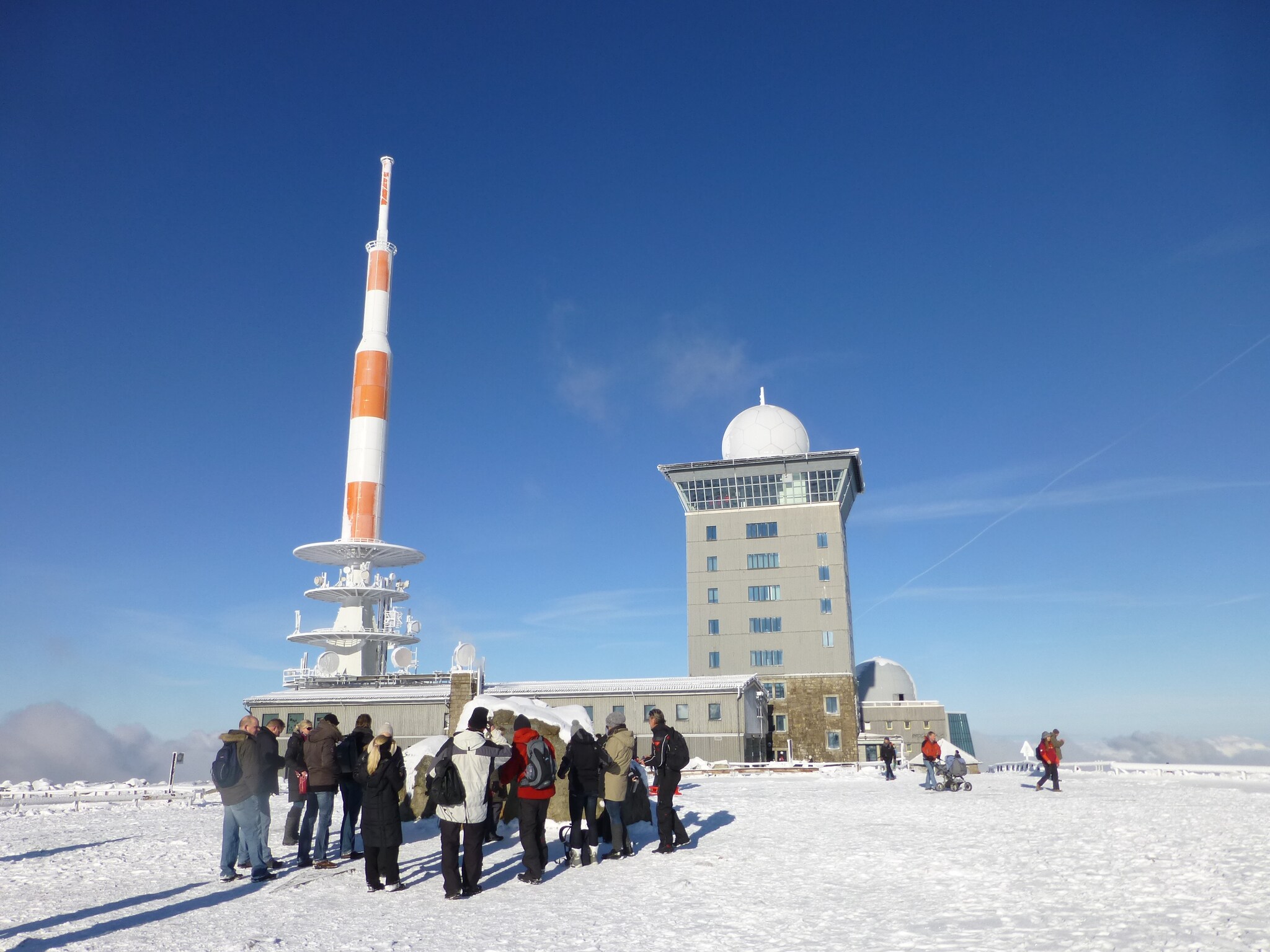 Eine Gruppe Touristen auf dem Gipfel des Brocken im Winter.