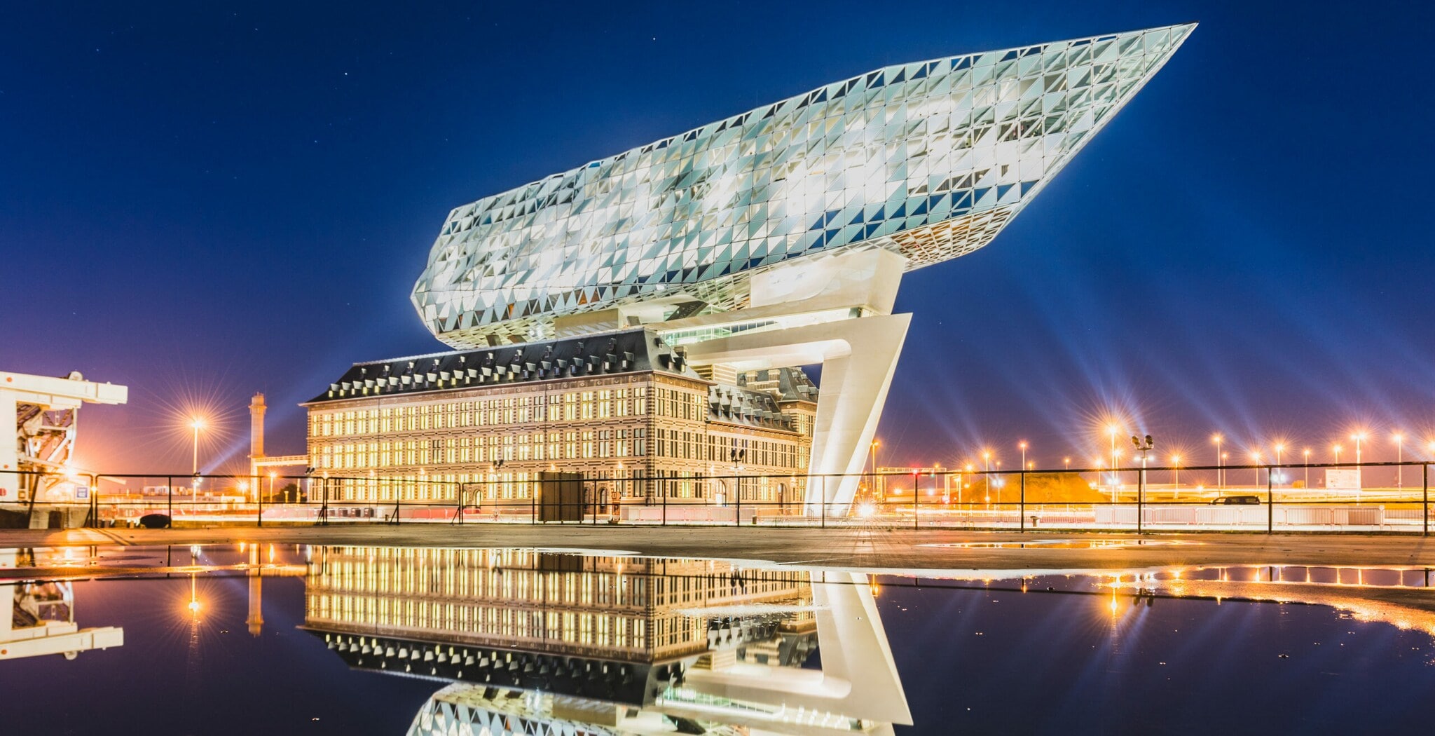 Ein futuristisches Bauwerk auf einem alten Gebäude, beide beleuchtet bei Nacht Ein futuristisches Bauwerk auf einem alten Gebäude, beide beleuchtet bei Nacht