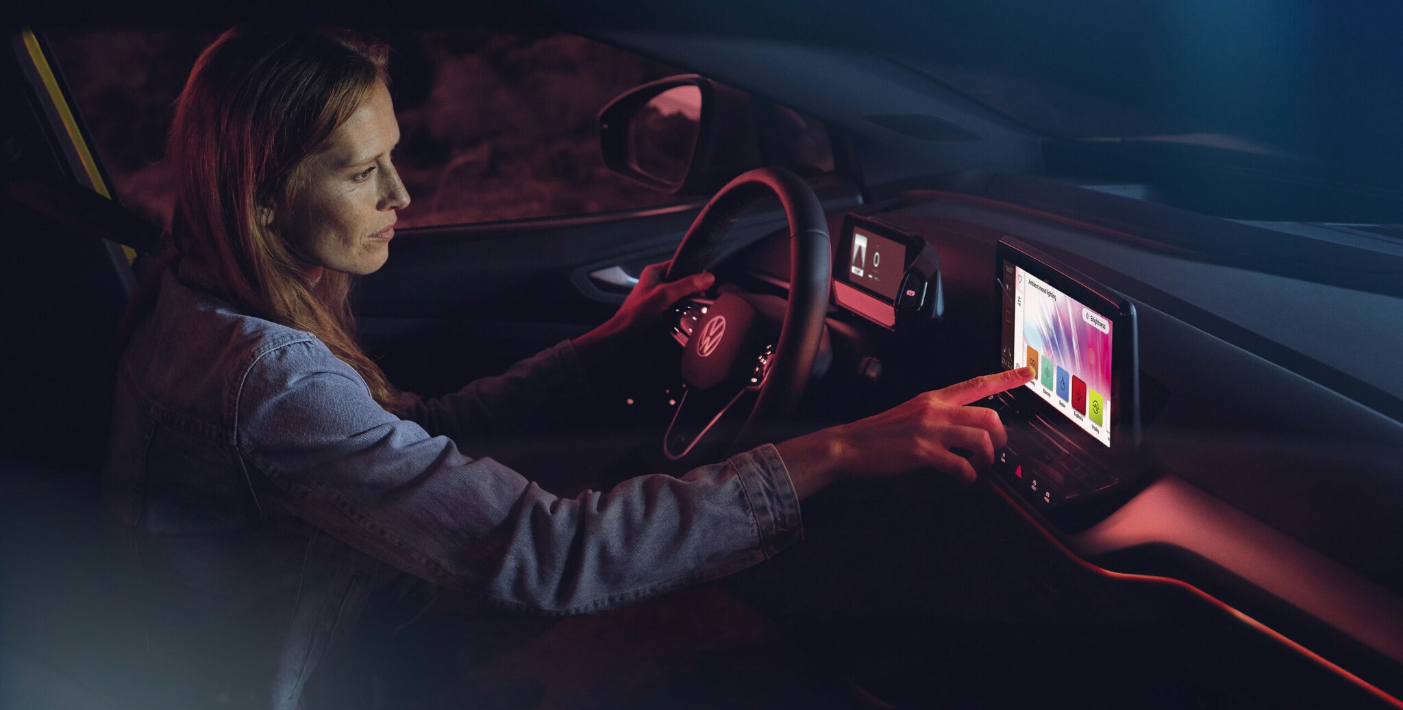 Ein Frau sitzt am Steuer ihres Autos und benutzt das intelligente System ihres Golfs.