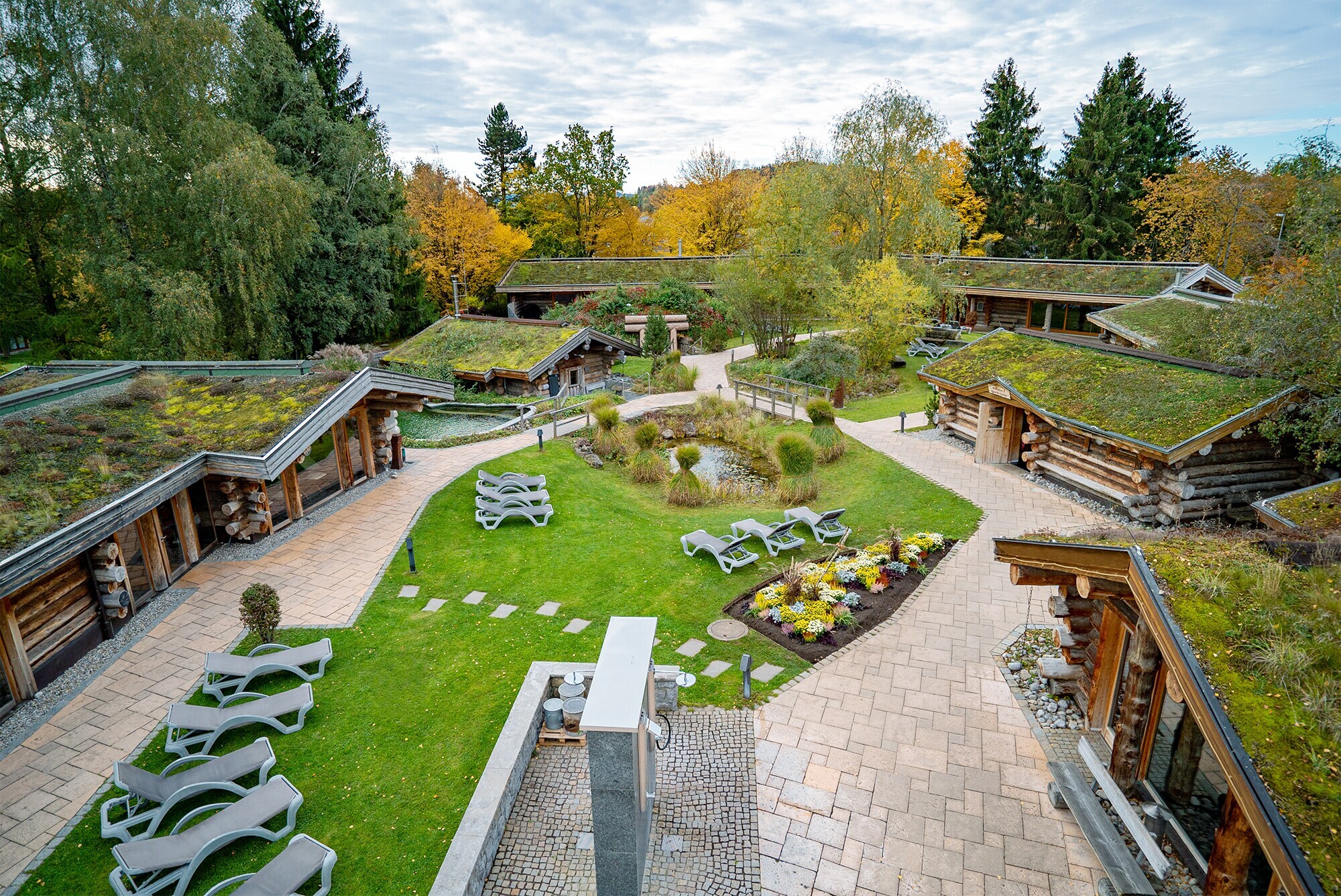 Aufsicht eines begrünten Saunagartens mit unterschiedlichen Schwitzhütten, die um eine Liegewiese angeordnet sind